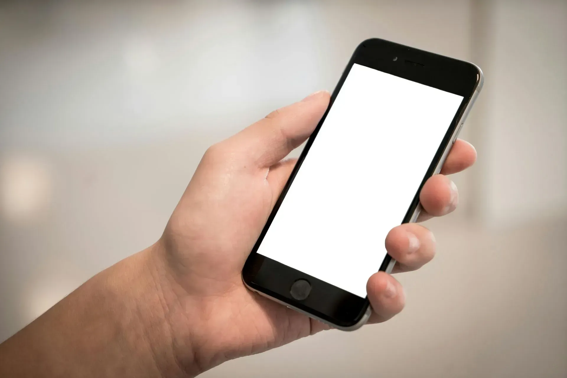 Hand Holding a Black Smartphone With a Blank White Screen — Micromac Computers in Charmhaven, NSW