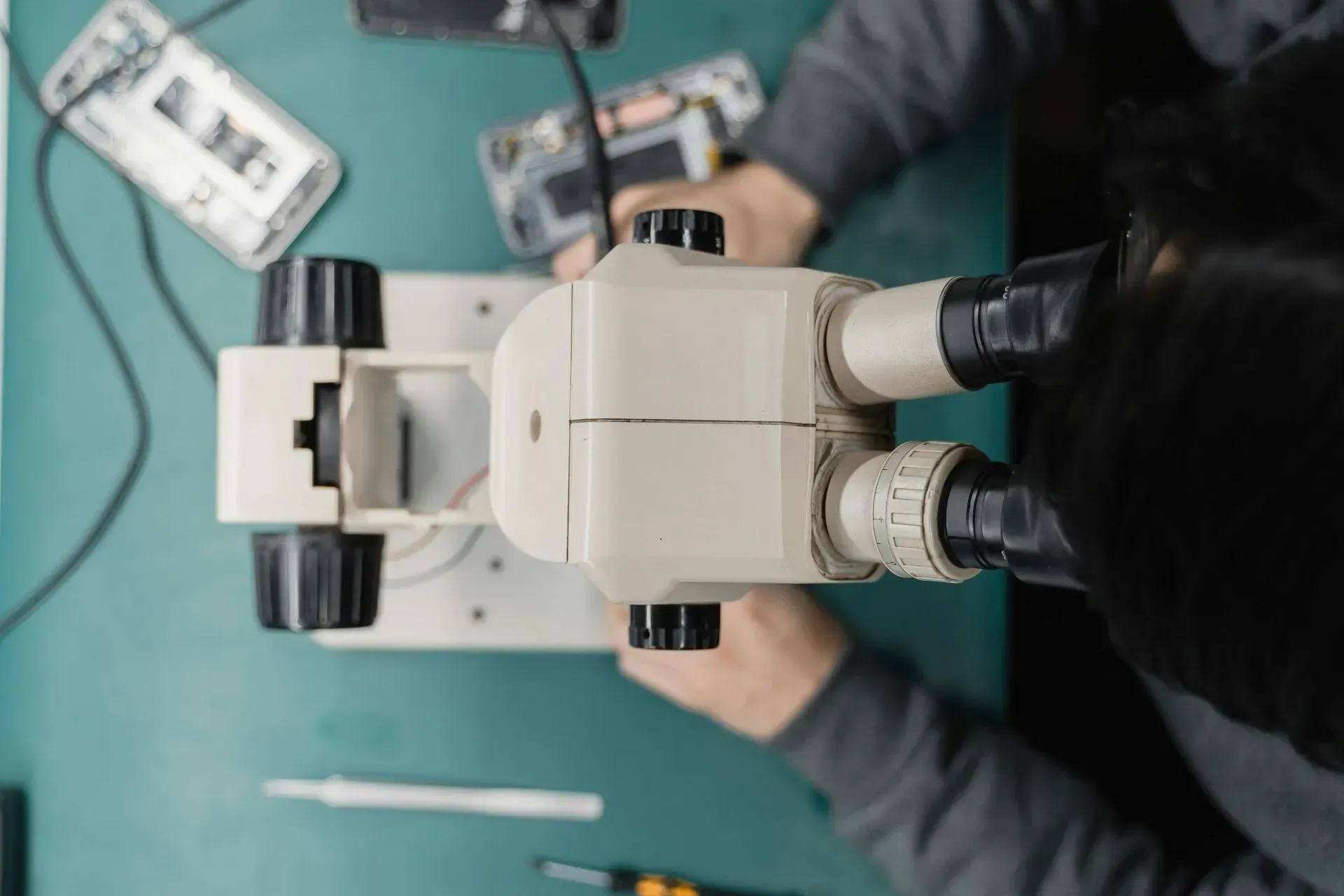 Person Using a Microscope to Repair a Phone on a Green Mat — Micromac Computers in Charmhaven, NSW