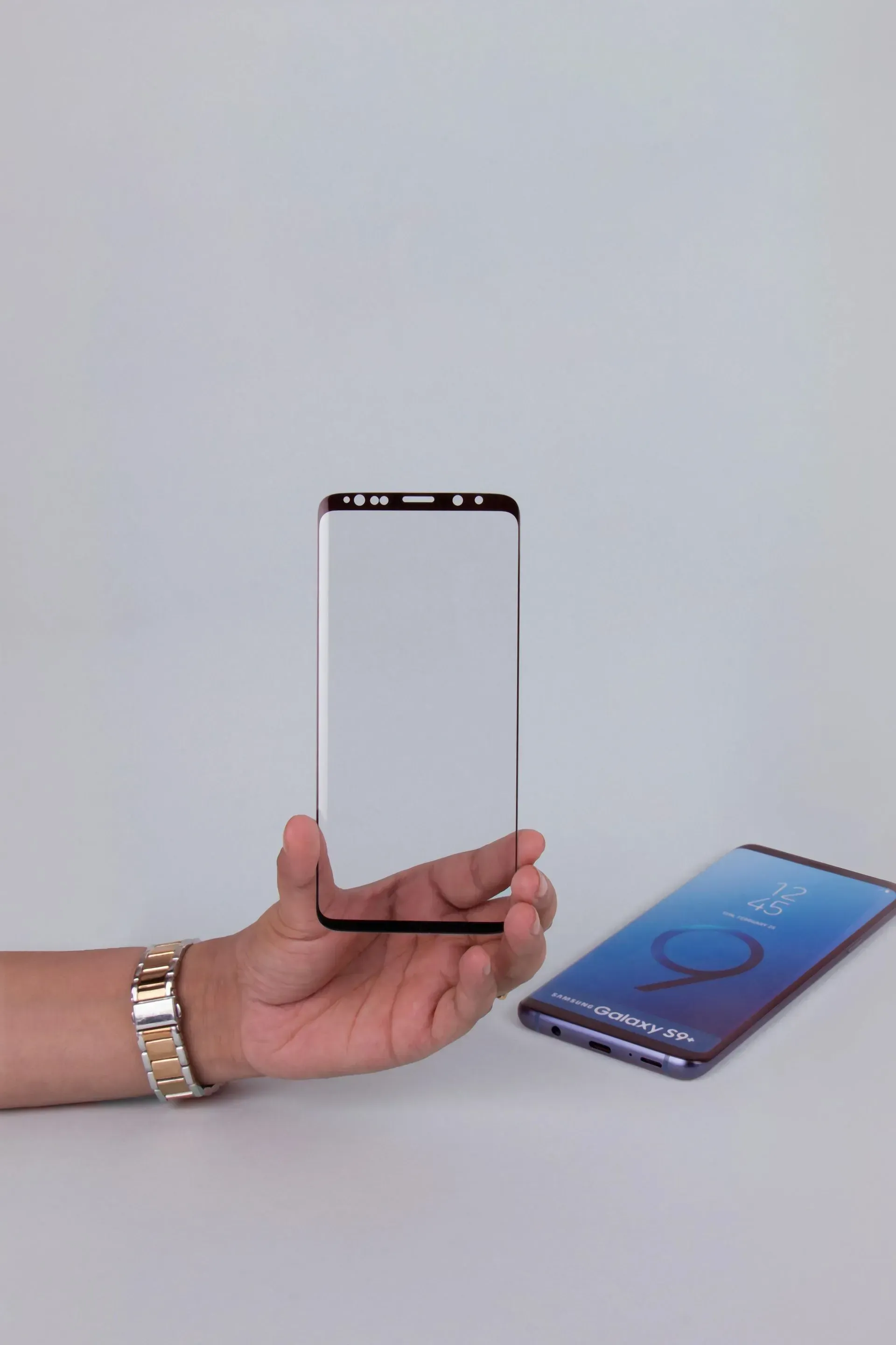 Hand Holding a Clear Phone Screen Protector Next to a Samsung Galaxy S9 Phone — Micromac Computers in Charmhaven, NSW