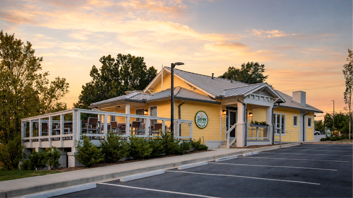 Low building with outdoor seating at sunset beside an empty parking lot