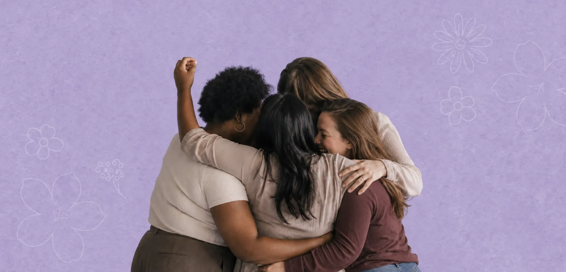 Three people hugging in a close group against a lavender wall.