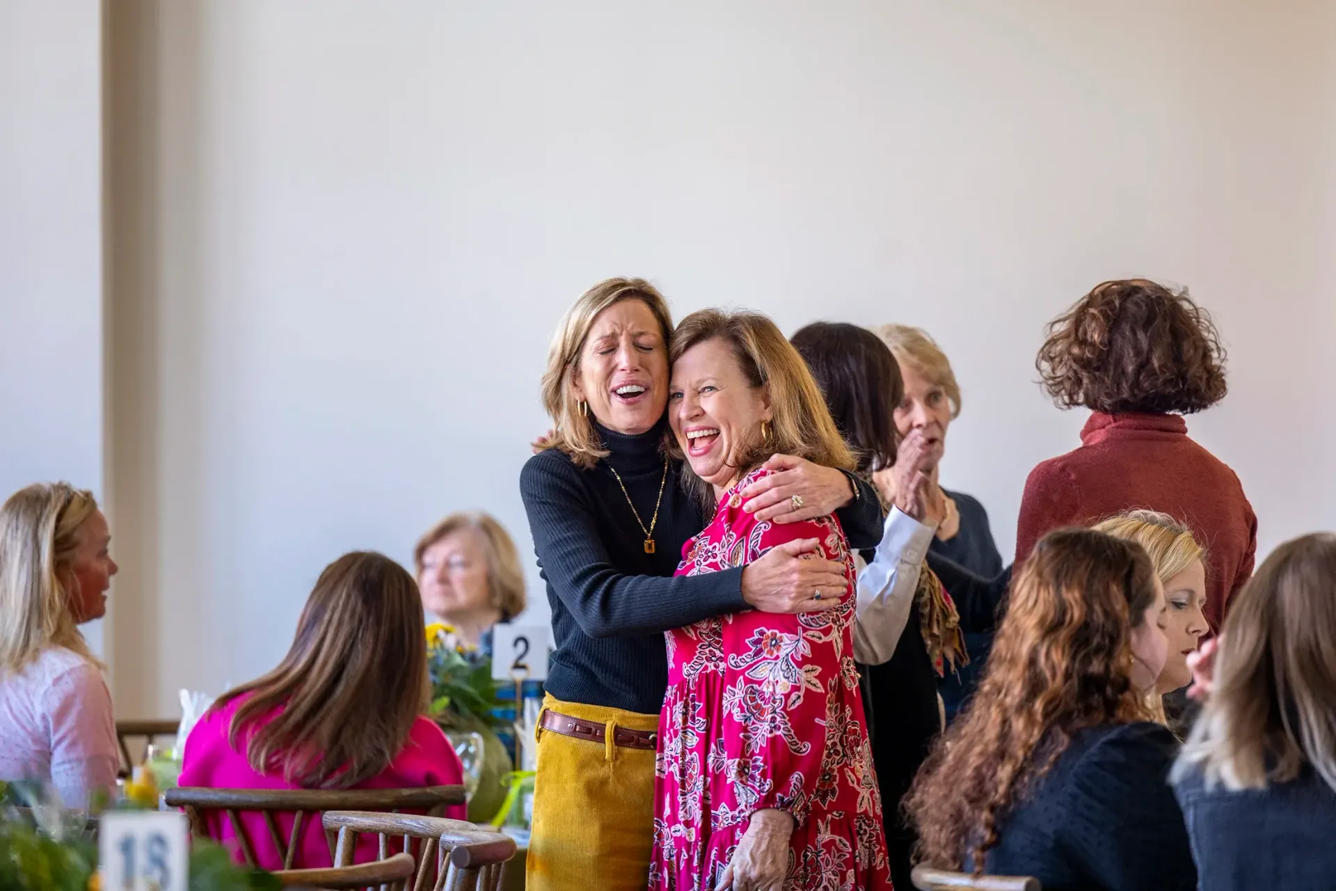 People hugging and smiling in a bright room during a lively gathering