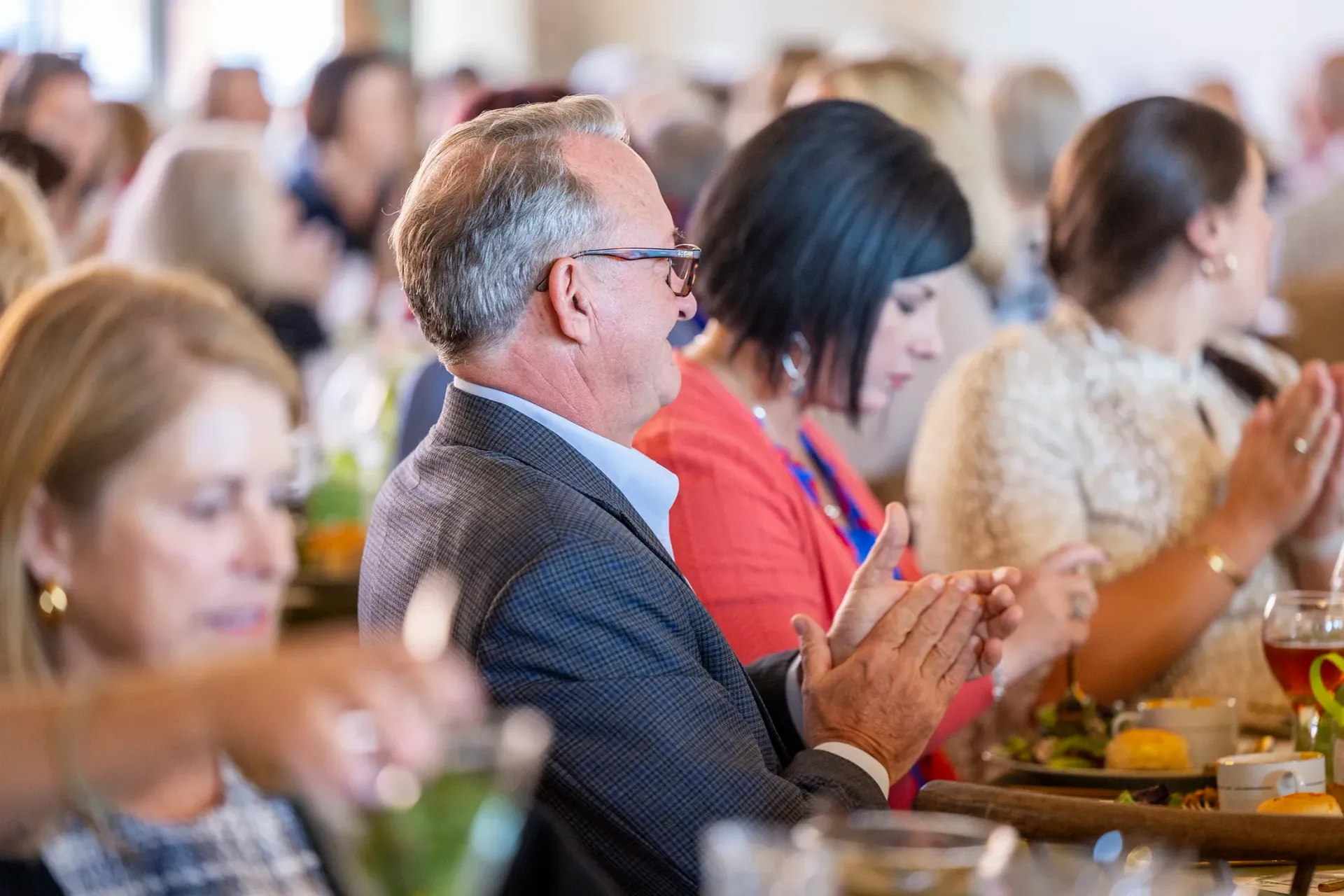 People seated at a banquet table applauding at an indoor event