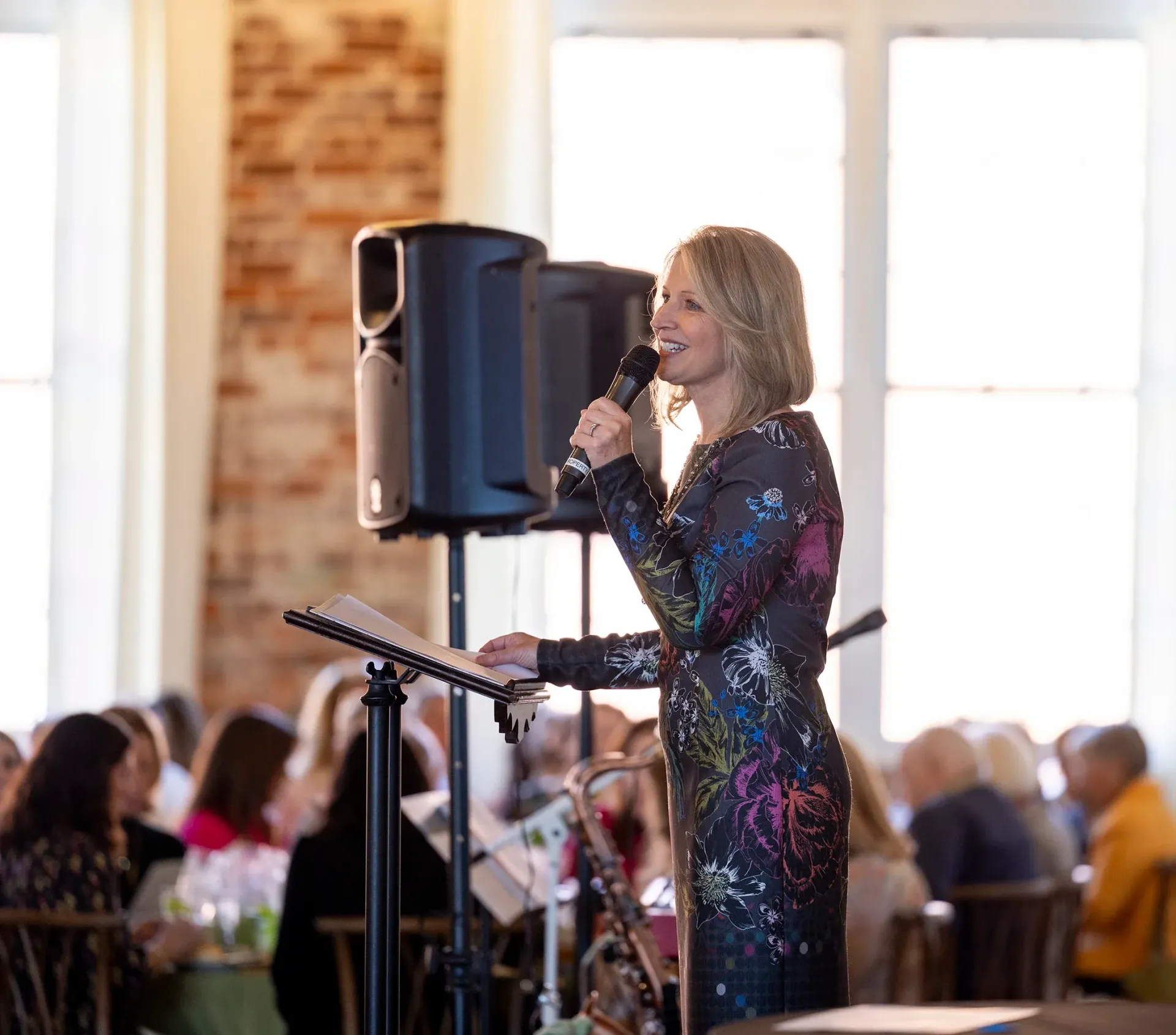 Singer in a sparkly dress performing with a microphone on a stage at an event
