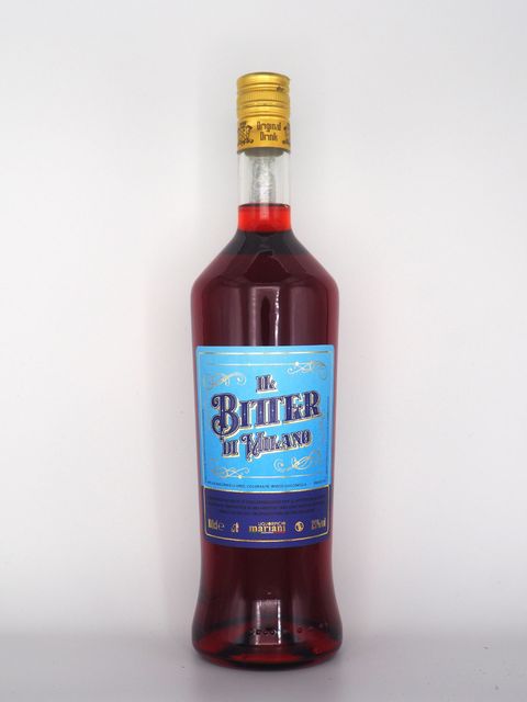 Bottiglia di Bitter Milano, liquido rosso, etichetta blu, tappo dorato.