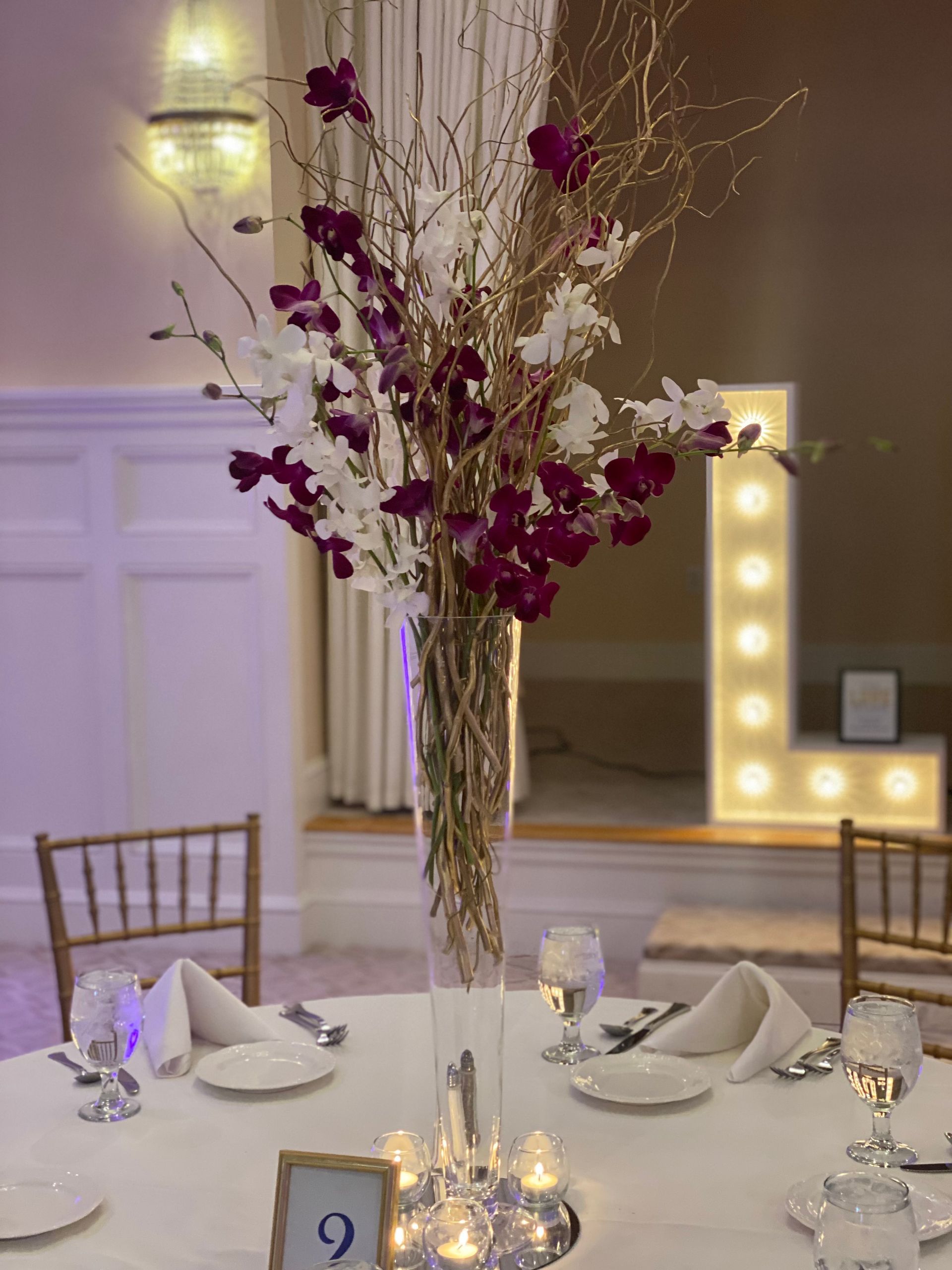 A tall vase filled with purple and white flowers sits on a table