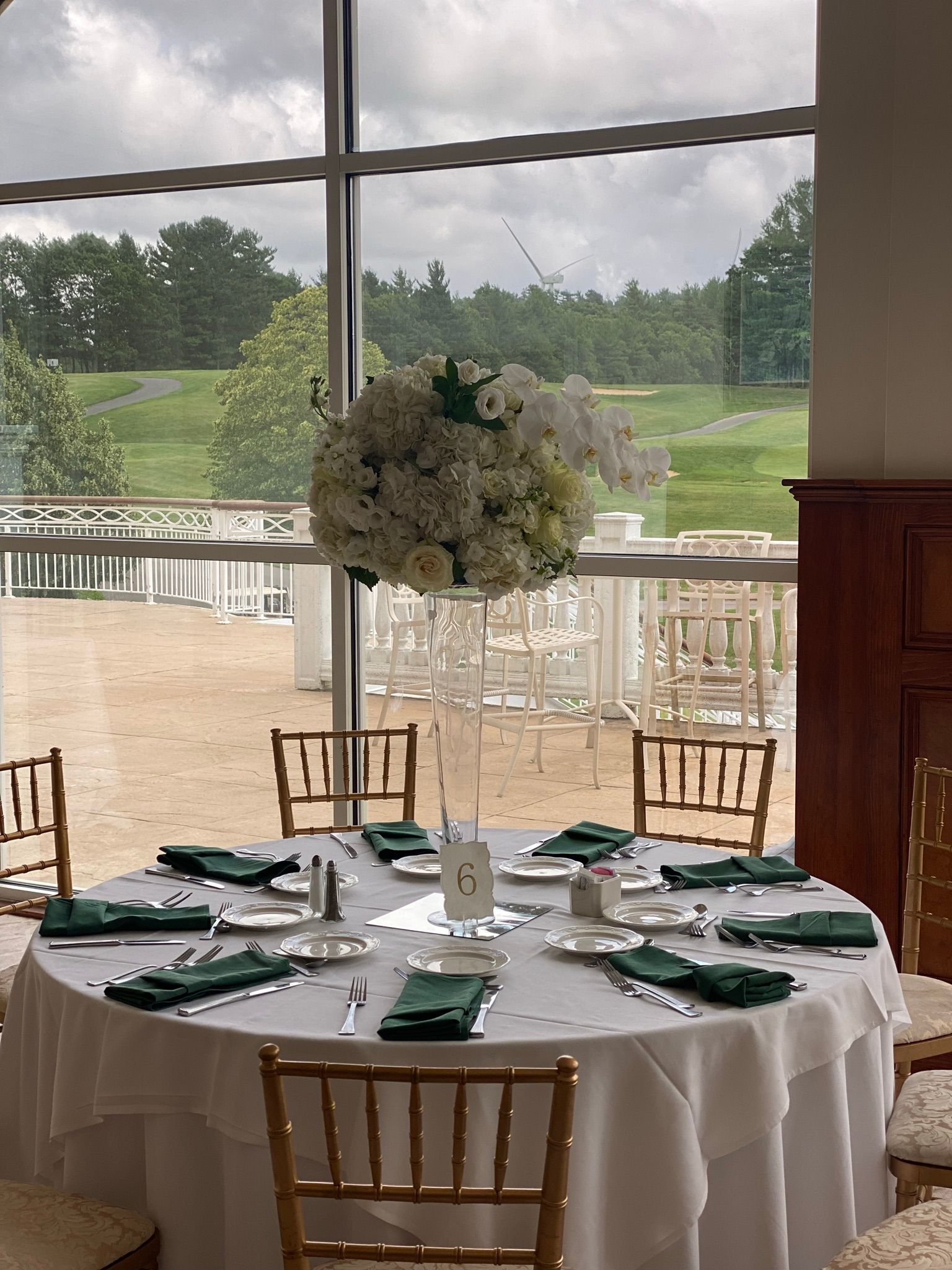 A table set for a wedding reception with a large vase of flowers on it.