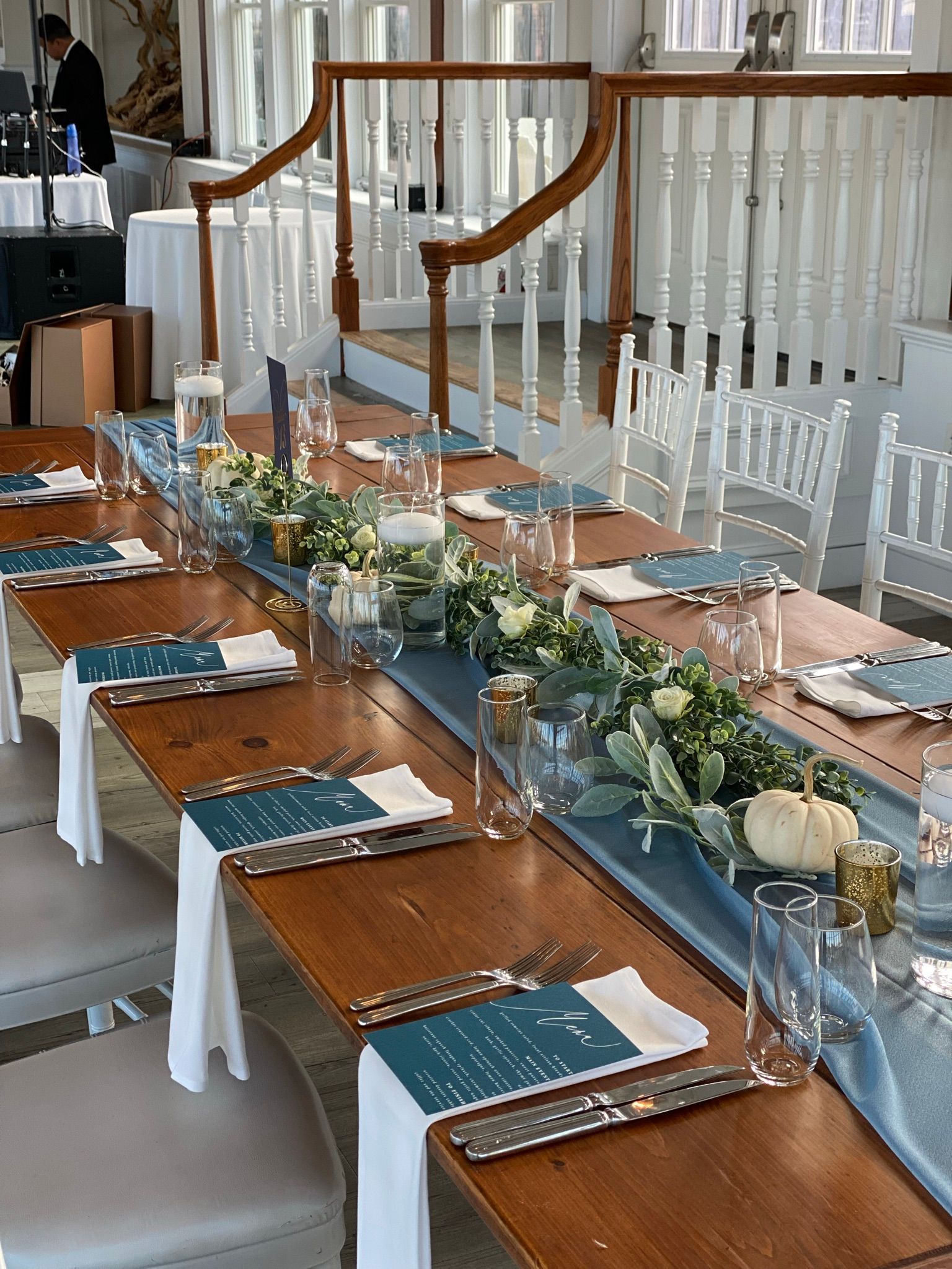 A long wooden table with plates , utensils , and flowers on it.