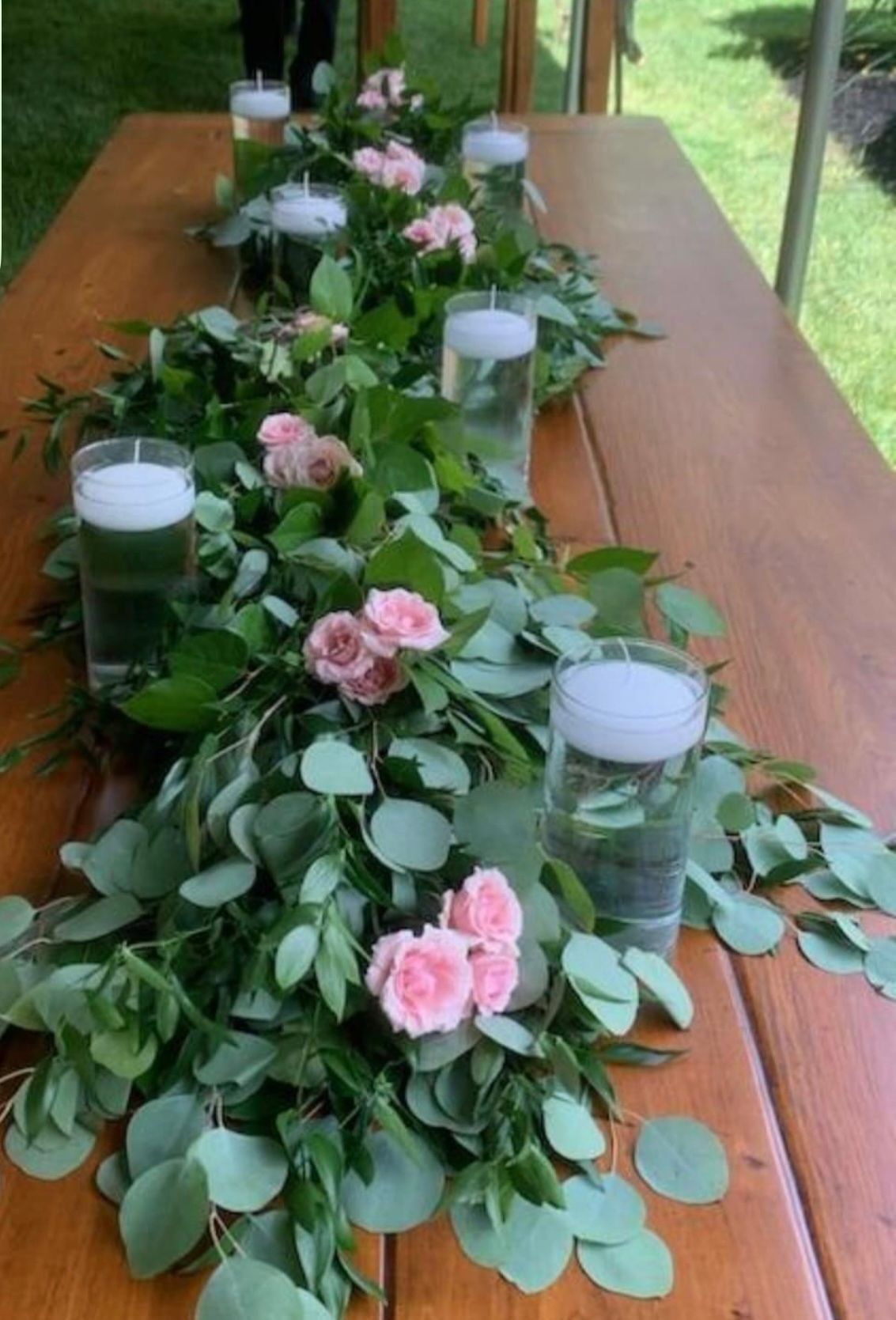 A long wooden table with flowers and candles on it.