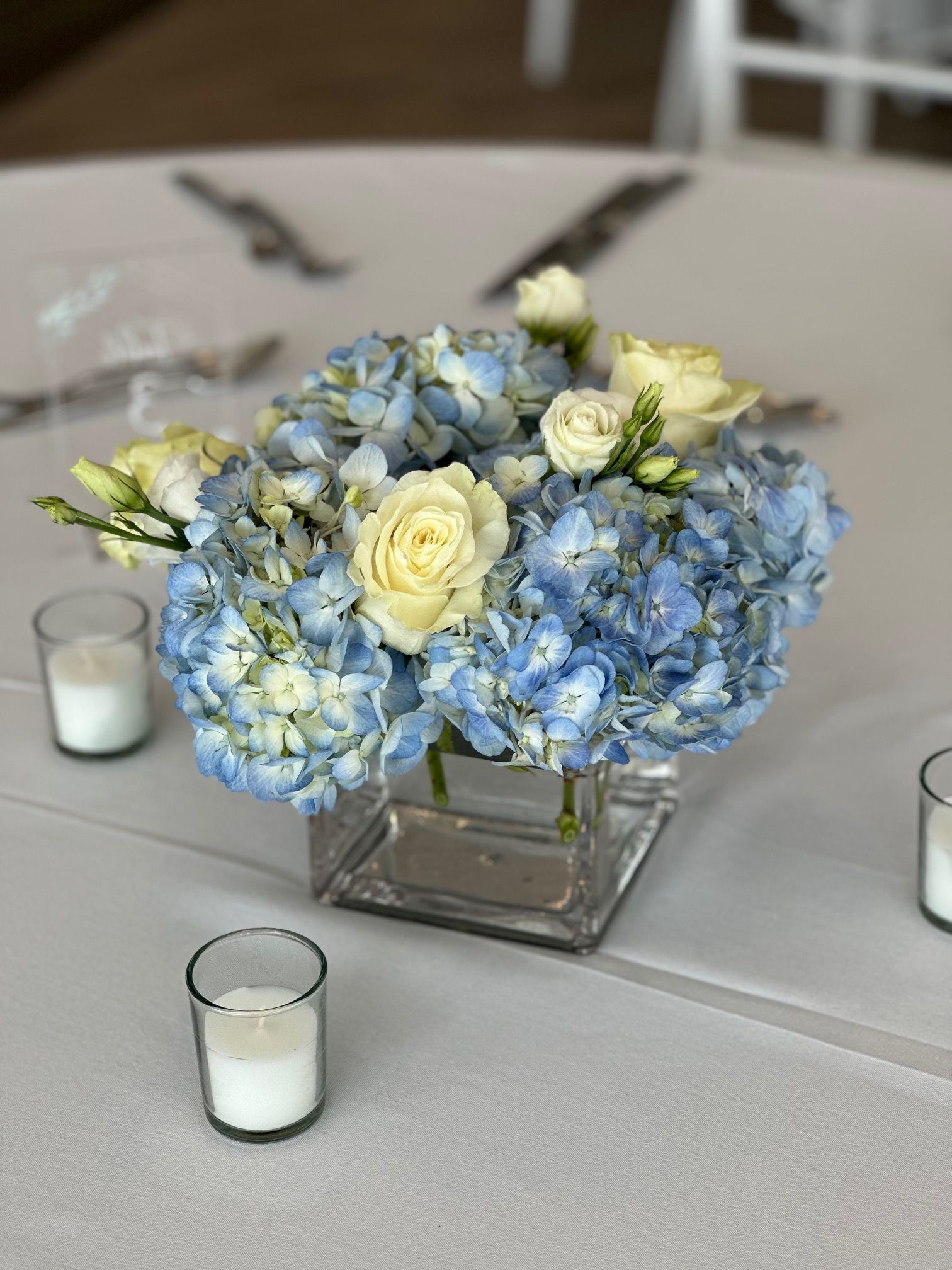 A vase filled with blue and white flowers and candles on a table.