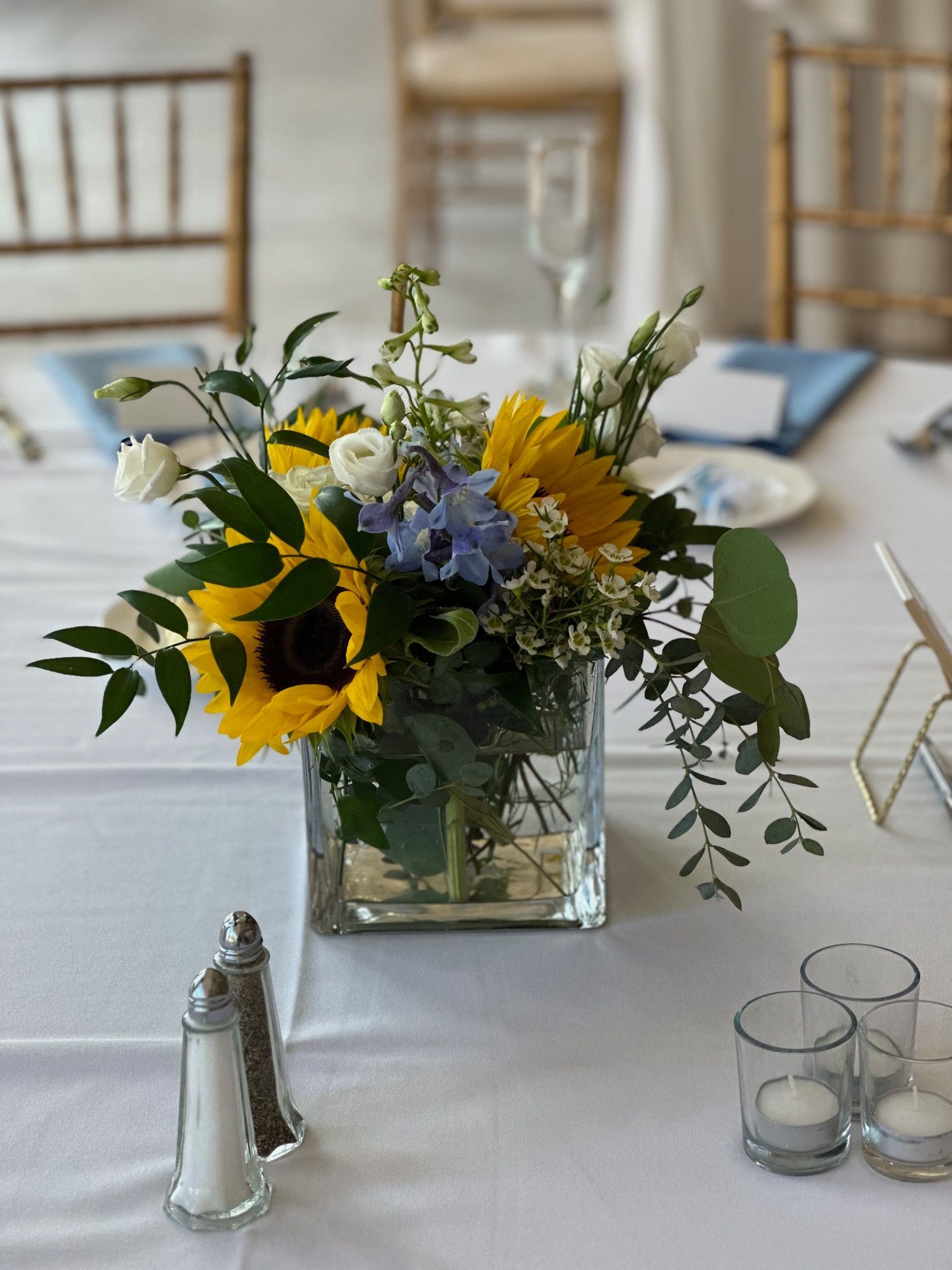 A vase filled with sunflowers and other flowers is on a table.