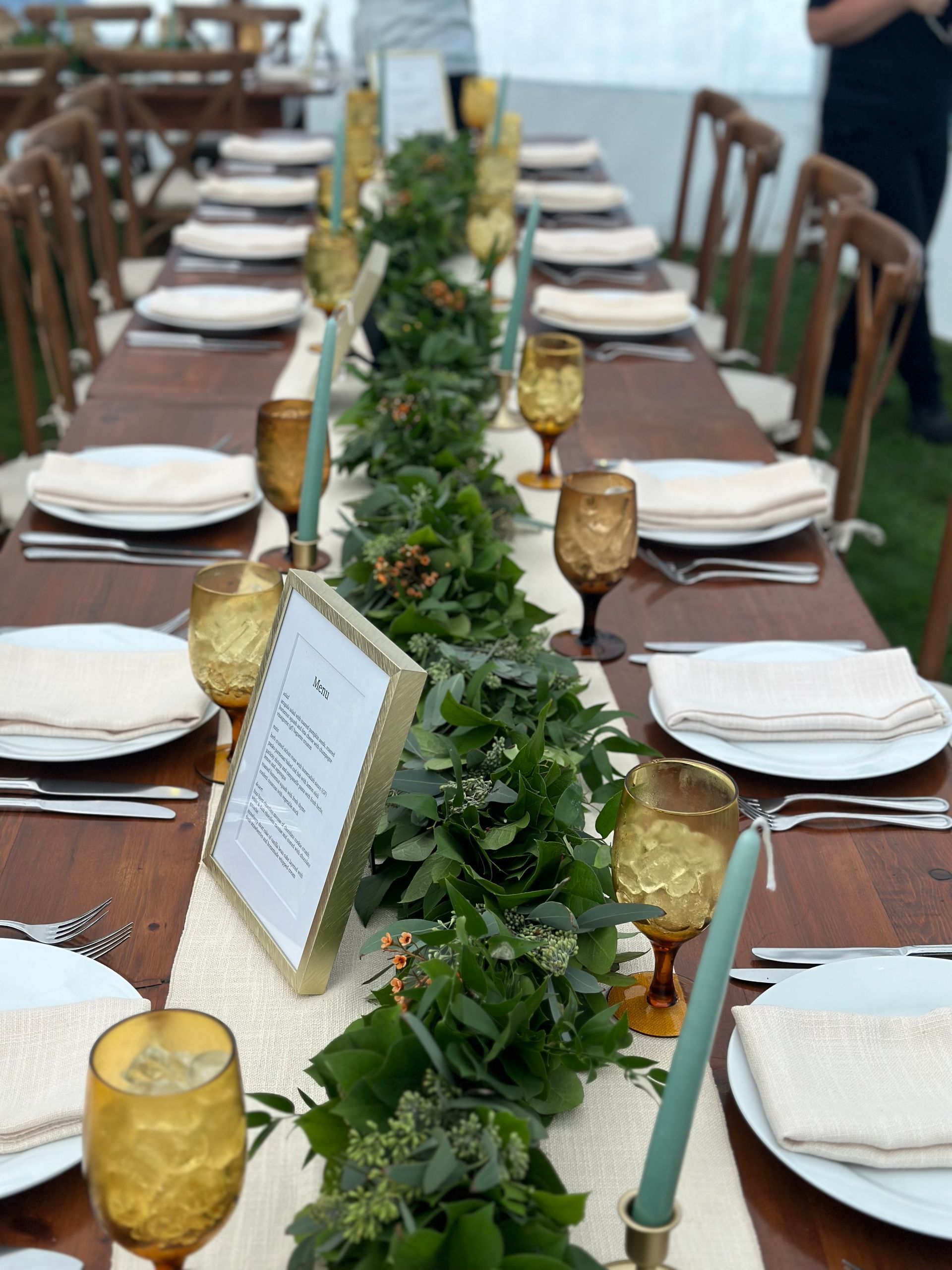 A long table with plates , candles and a sign that says ' dinner ' on it