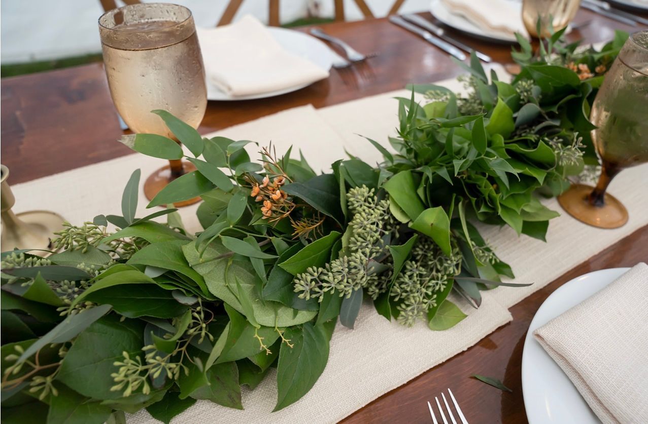 A table with a garland of greenery and flowers on it.