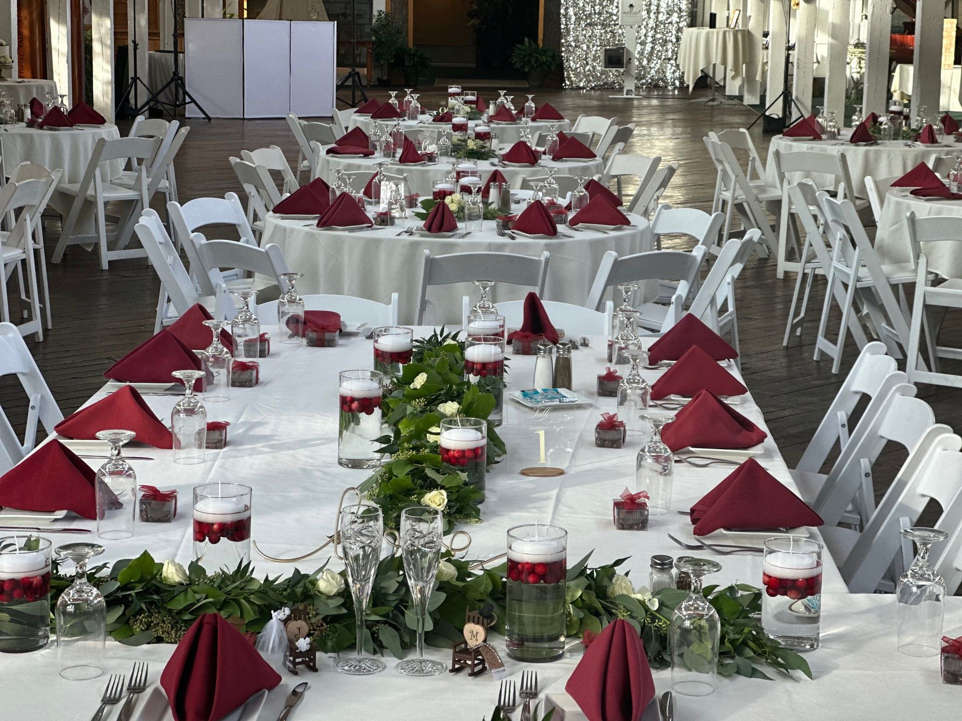 A long table set up for a wedding reception with red napkins and candles.