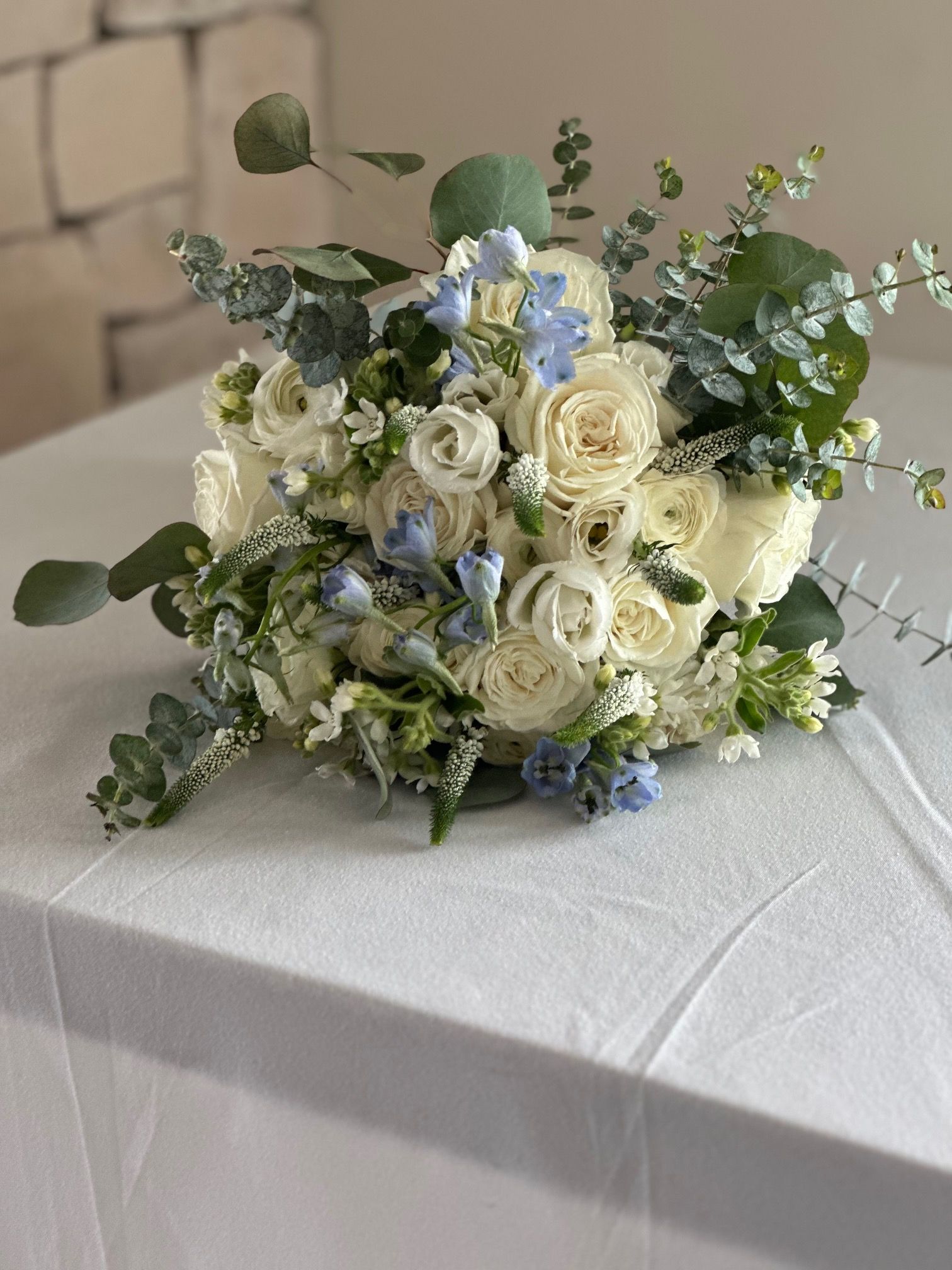 A bouquet of white roses and blue flowers is sitting on a table.