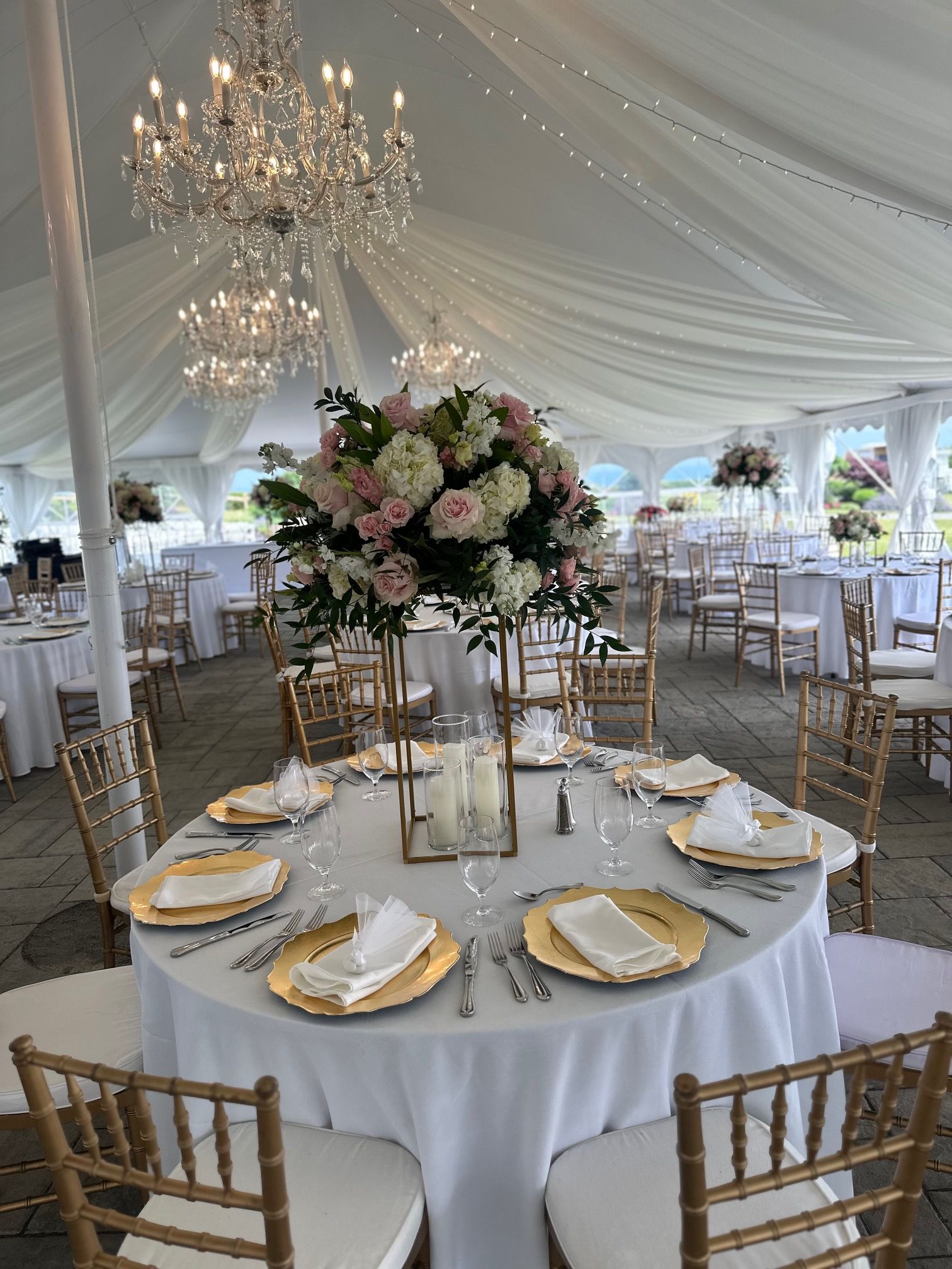 A large tent with tables and chairs set up for a wedding reception.
