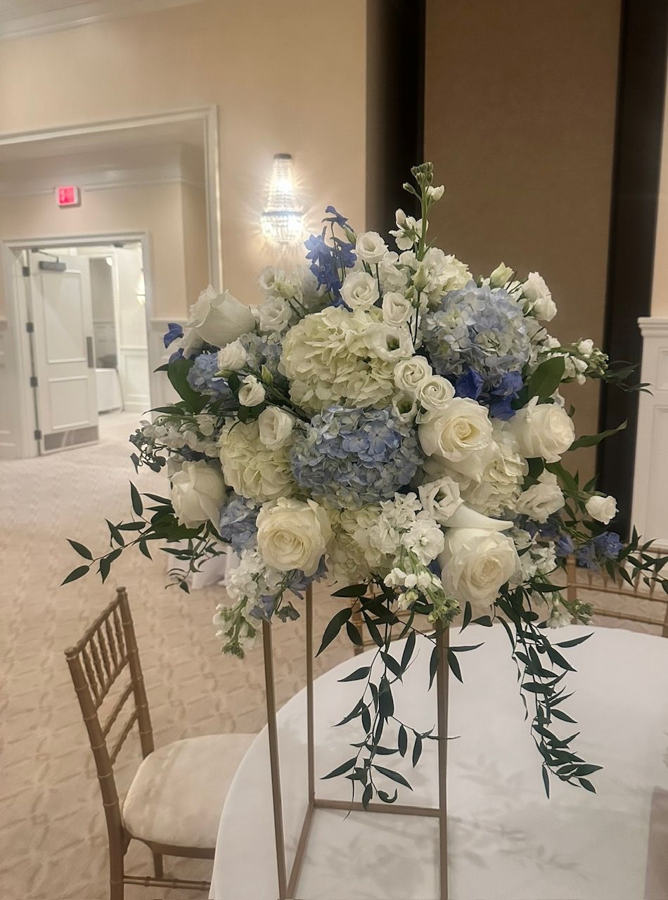 A table with a vase of blue and white flowers on it.