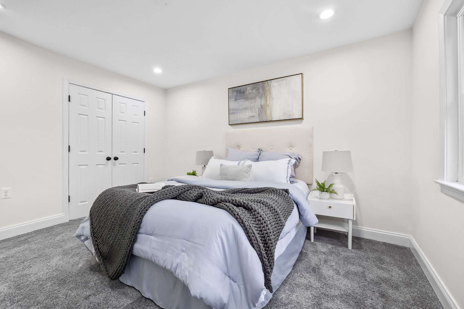 A bedroom with a bed , nightstand , and window.