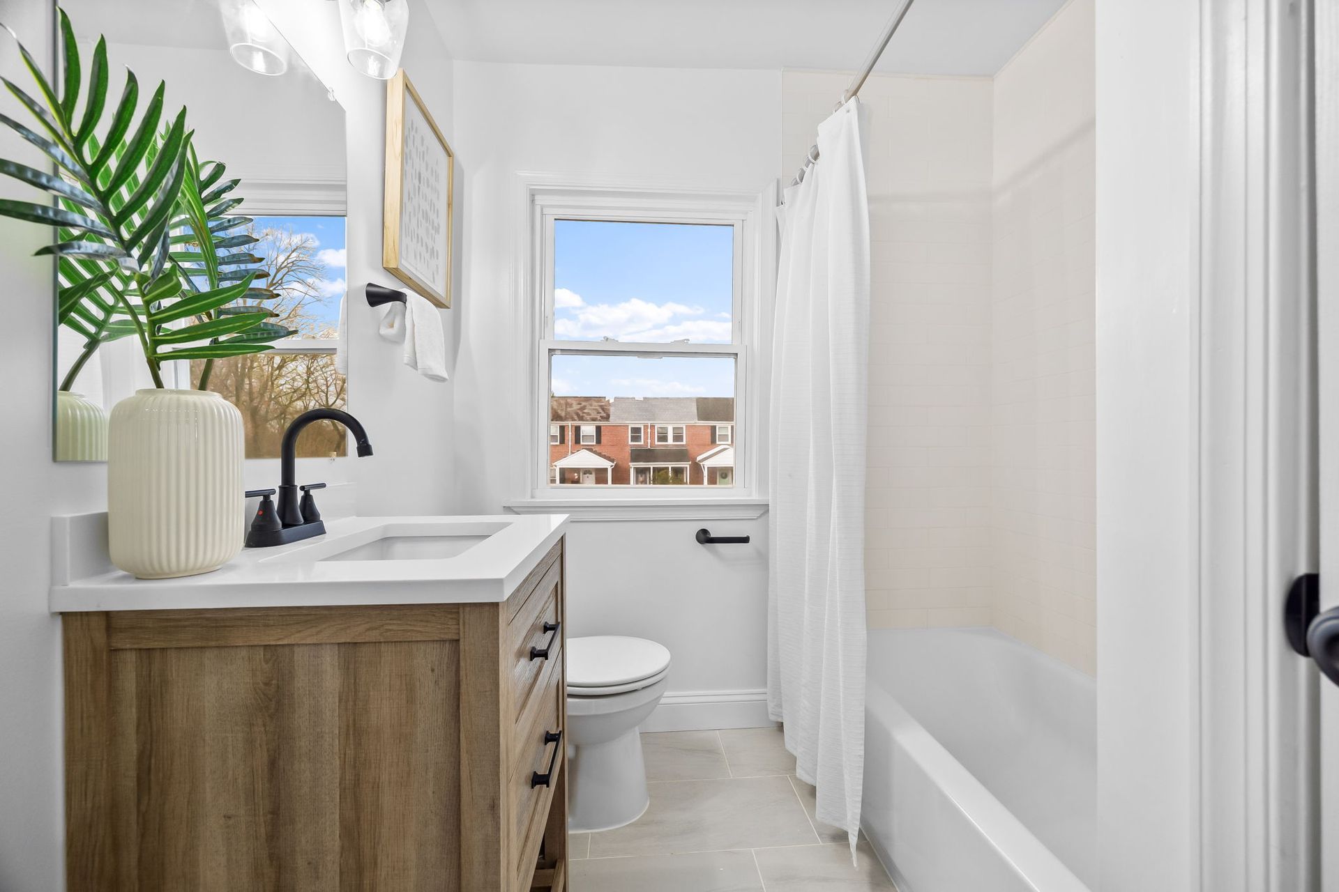 A bathroom with a sink , toilet , shower and window.