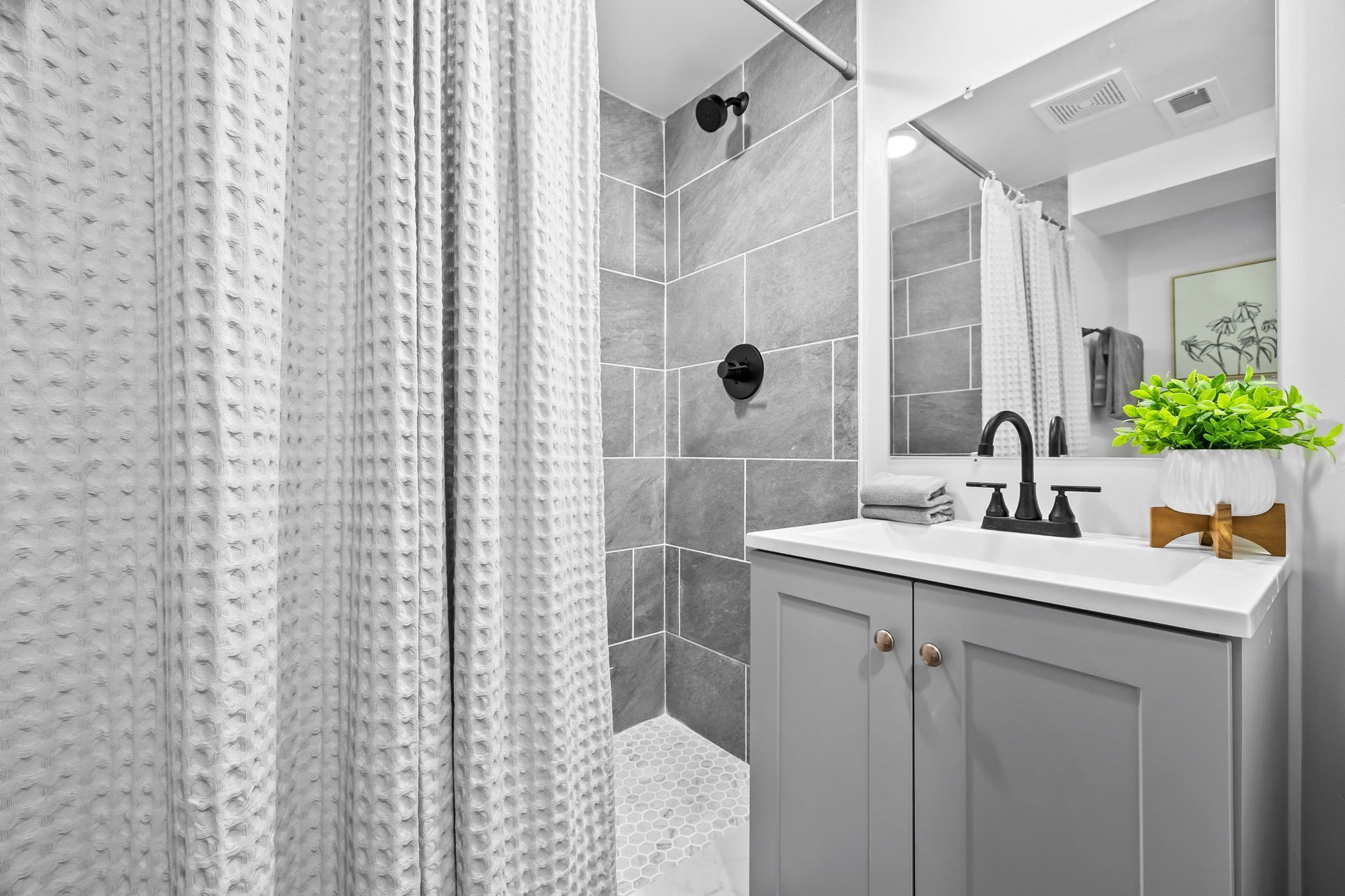 A bathroom with a shower , sink , mirror and shower curtain.