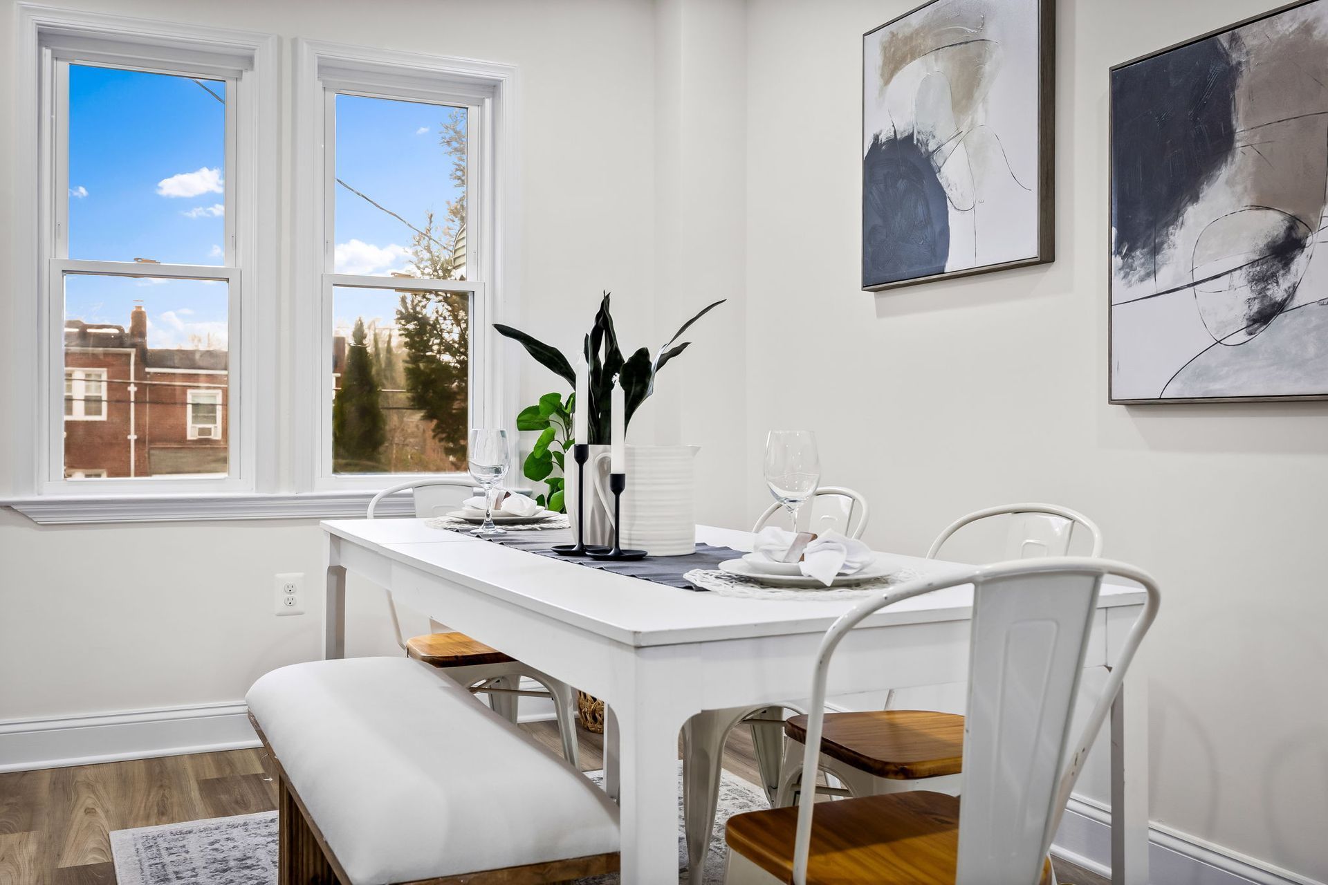 A dining room with a white table and chairs and a window.