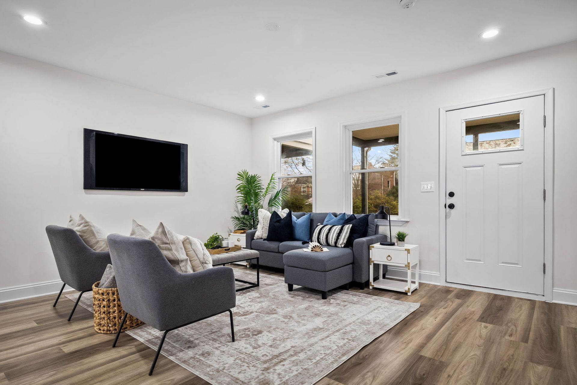 A living room with a couch , chairs , and a flat screen tv.