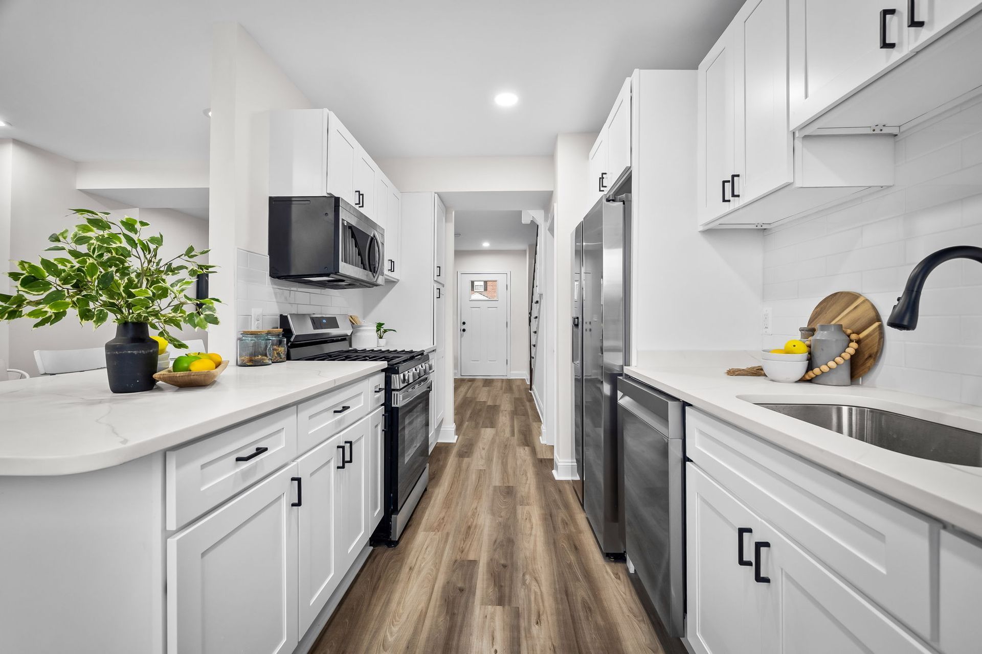 A kitchen with white cabinets , stainless steel appliances , and hardwood floors.