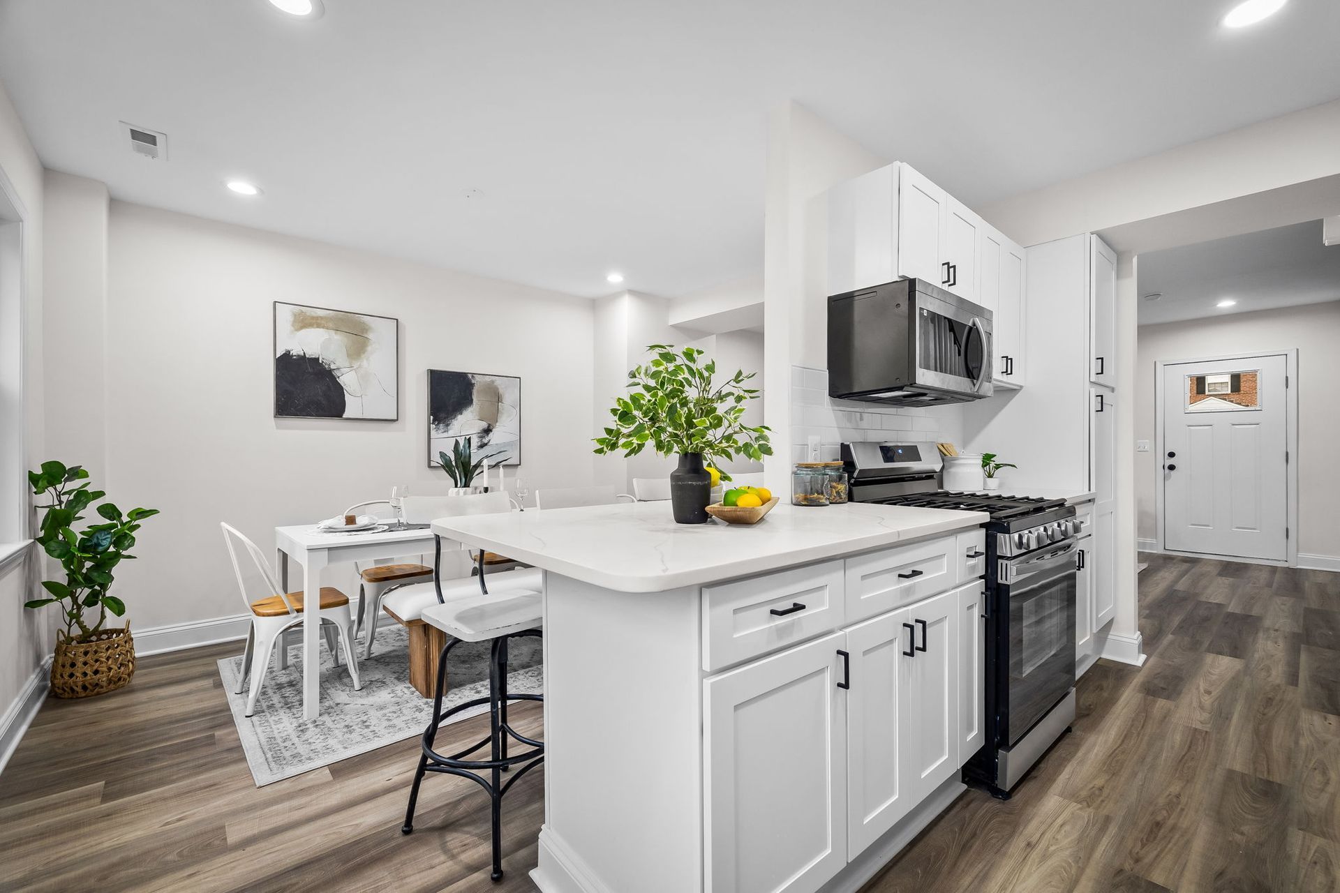 A kitchen with white cabinets , stainless steel appliances , a stove and a microwave.
