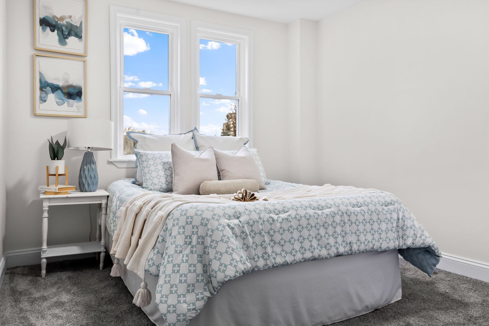 A bedroom with a bed , nightstand , and two windows.