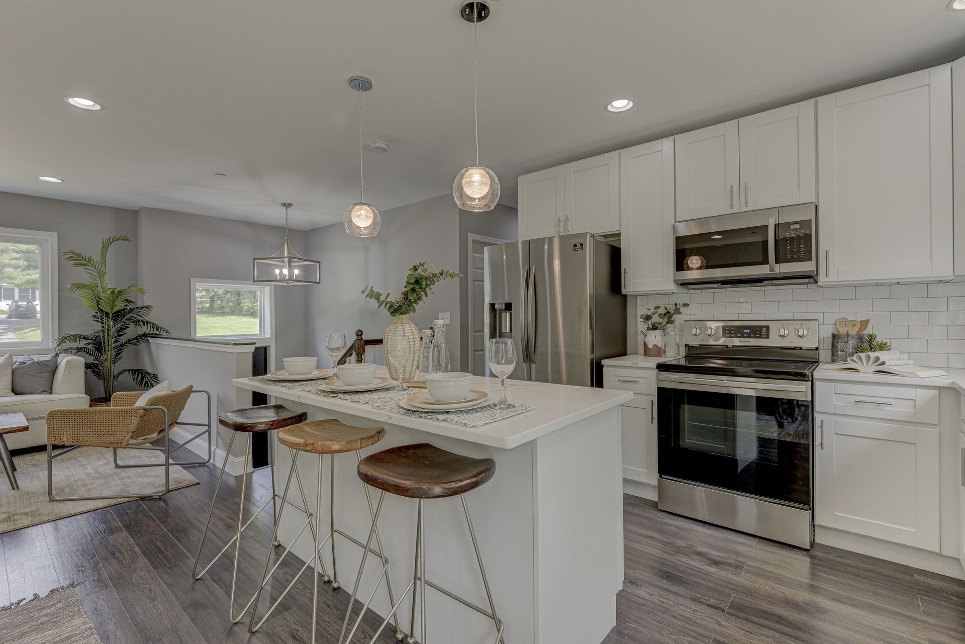 A kitchen with white cabinets and stainless steel appliances and a large island.