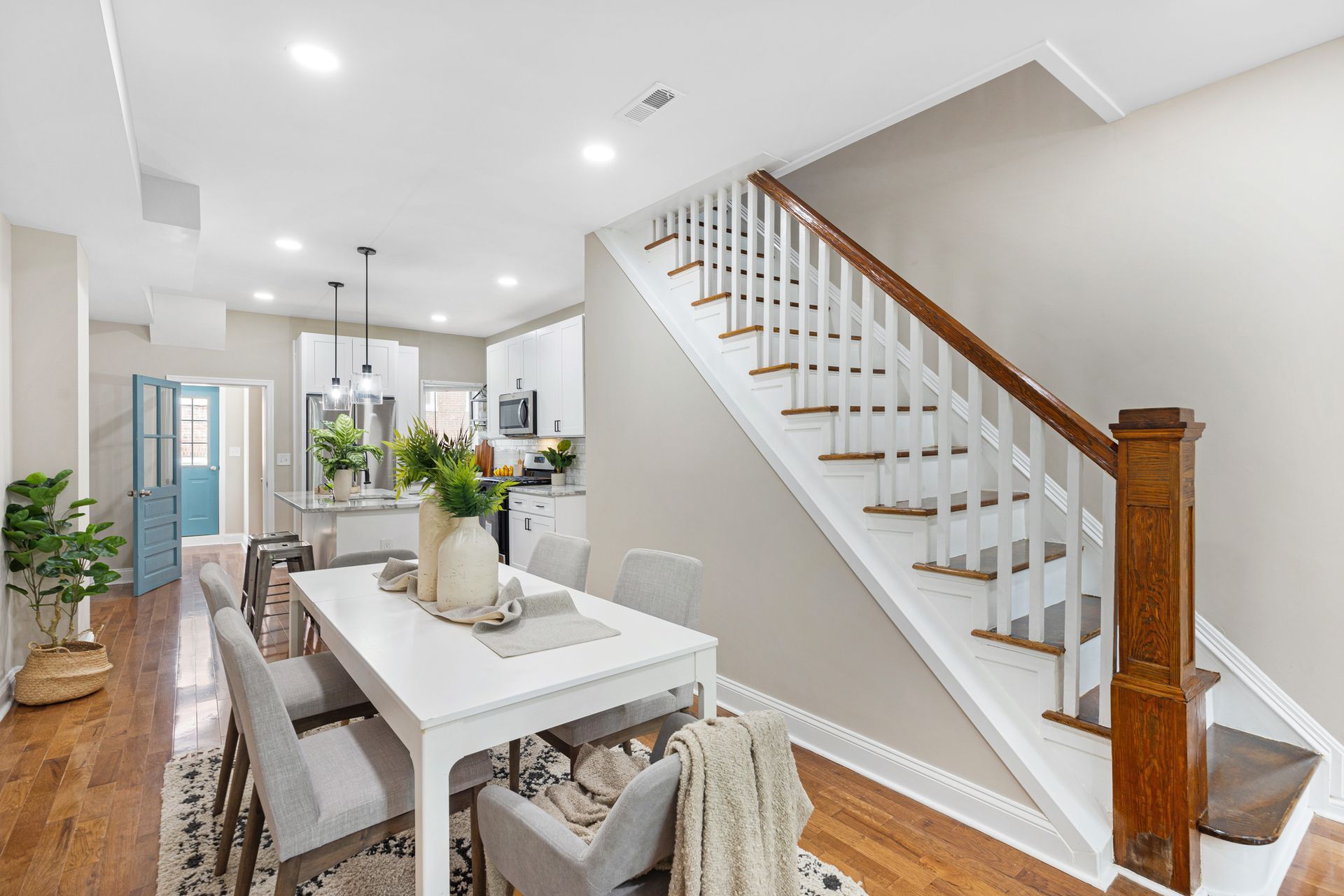 A dining room with a table and chairs and stairs leading up to the second floor.