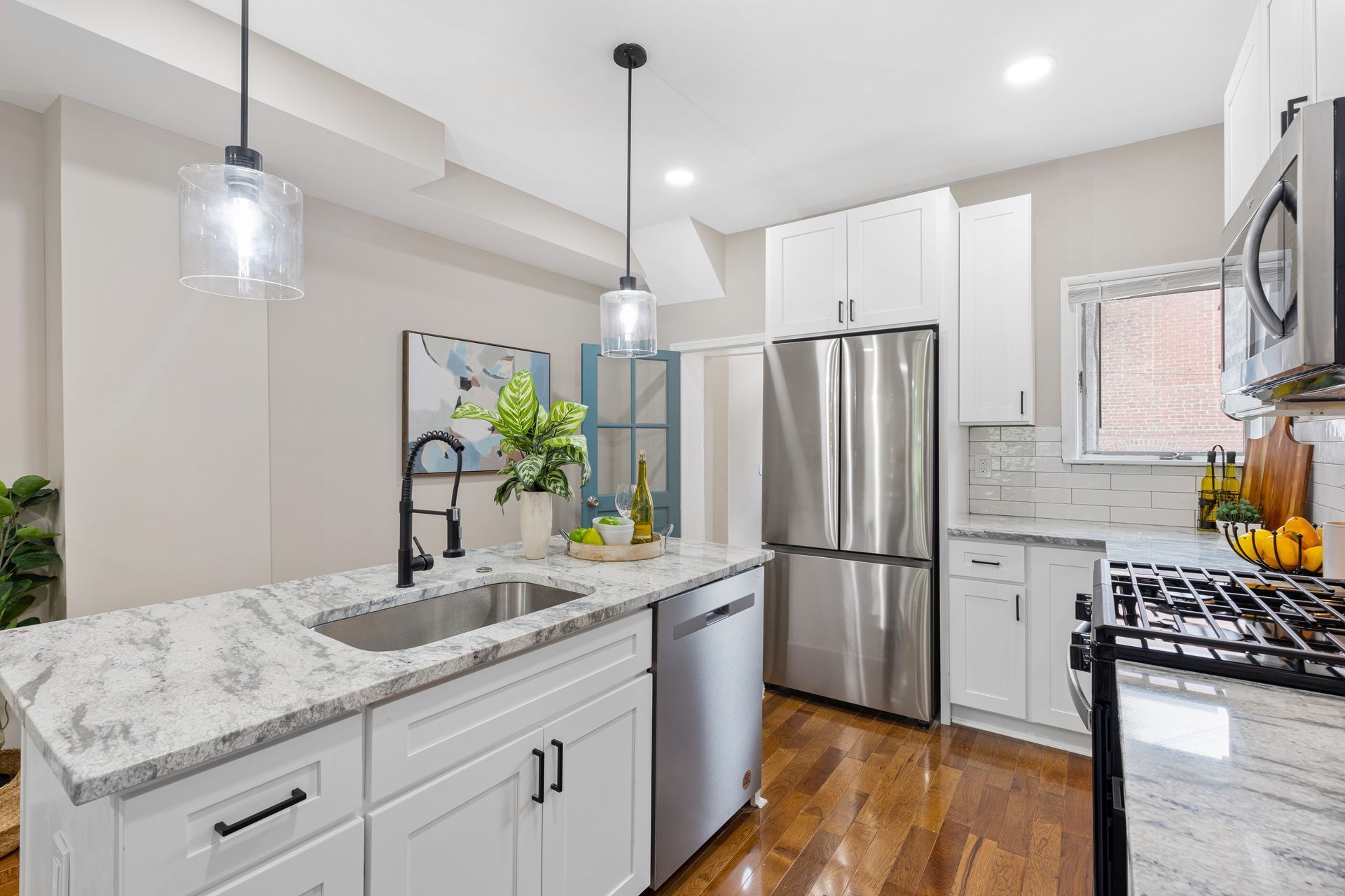 A kitchen with white cabinets , granite counter tops , stainless steel appliances and a sink.