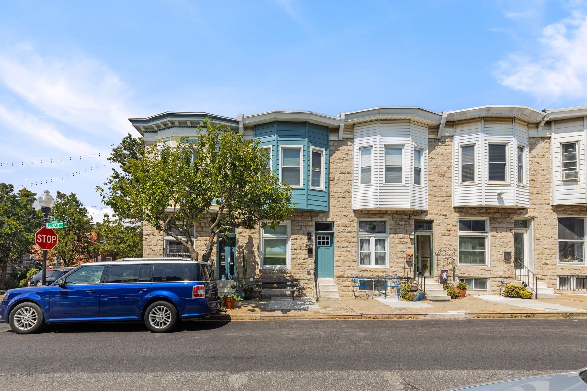 A blue car is parked in front of a row of houses.