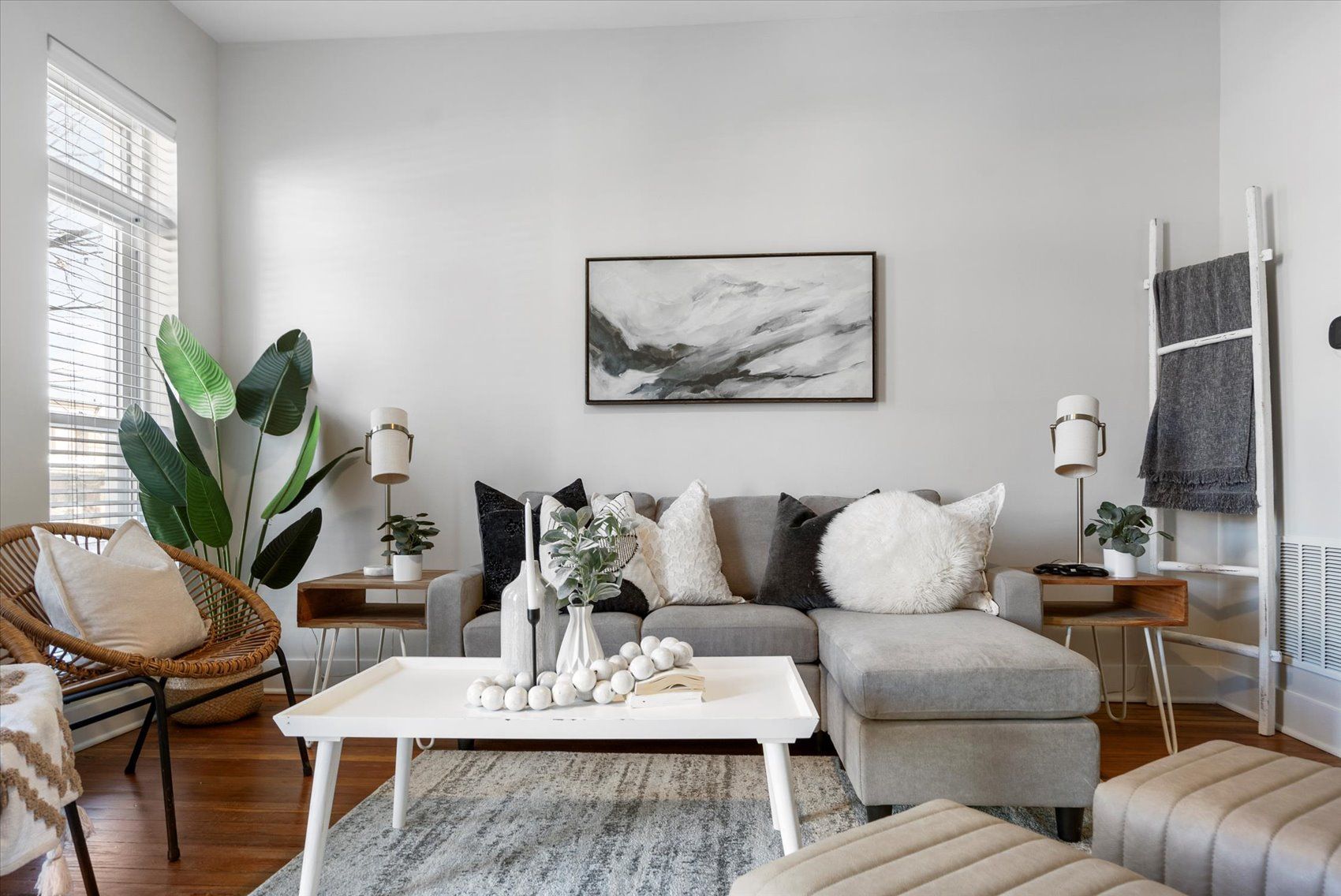 A living room with a couch , coffee table , chairs and a painting on the wall.
