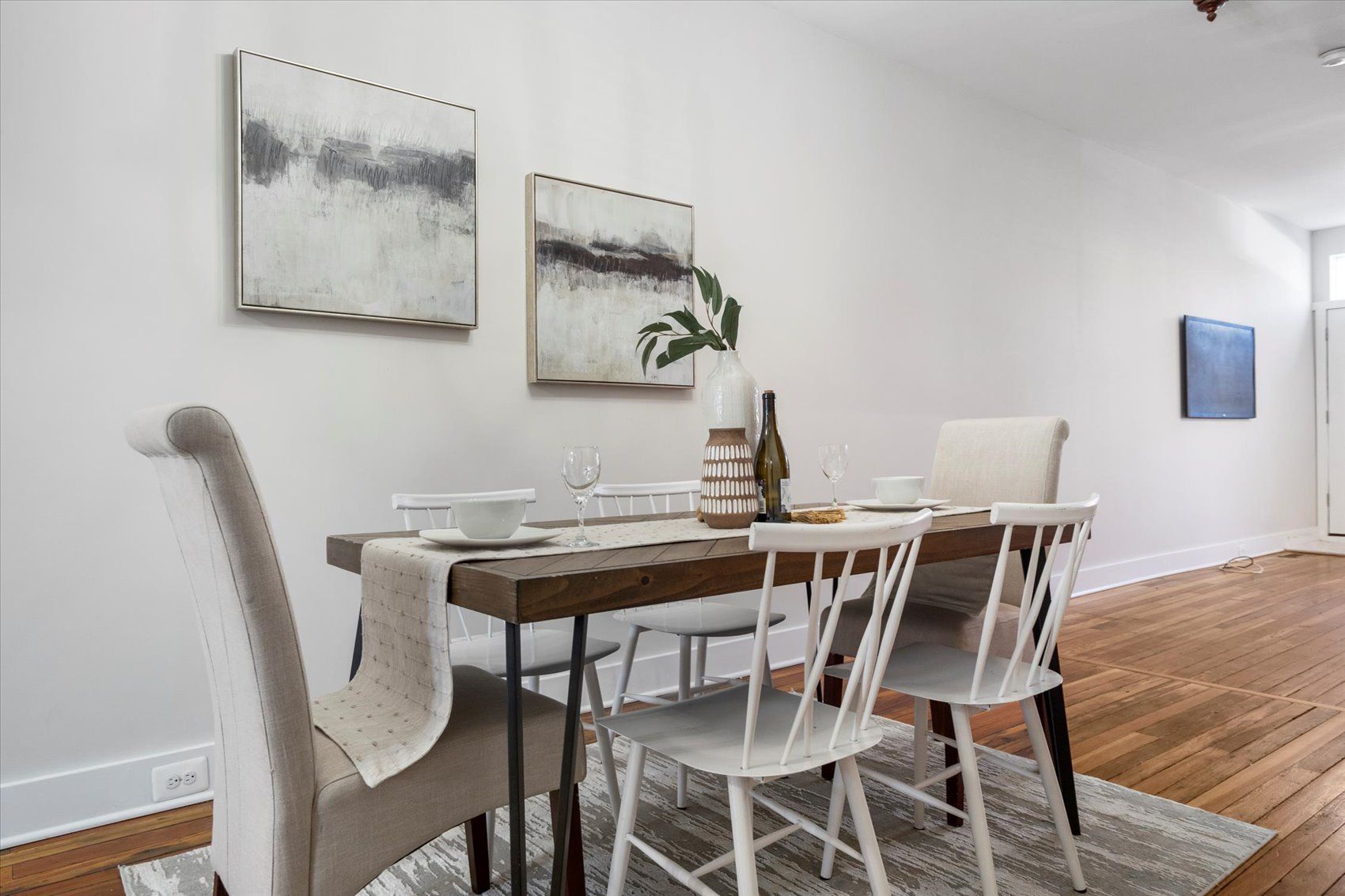 A dining room with a wooden table and white chairs.