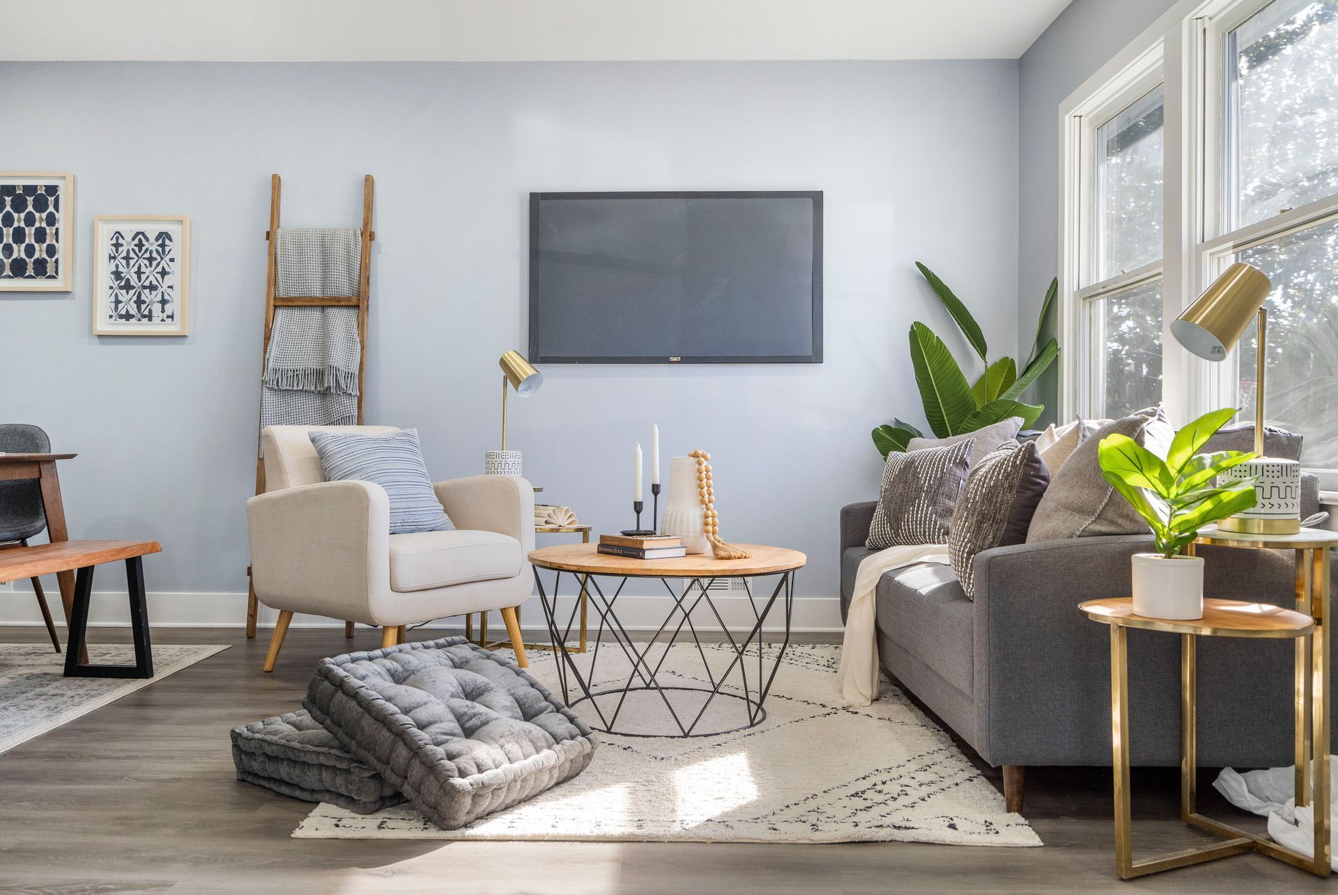 A living room with a couch , chairs , tables and a flat screen tv.