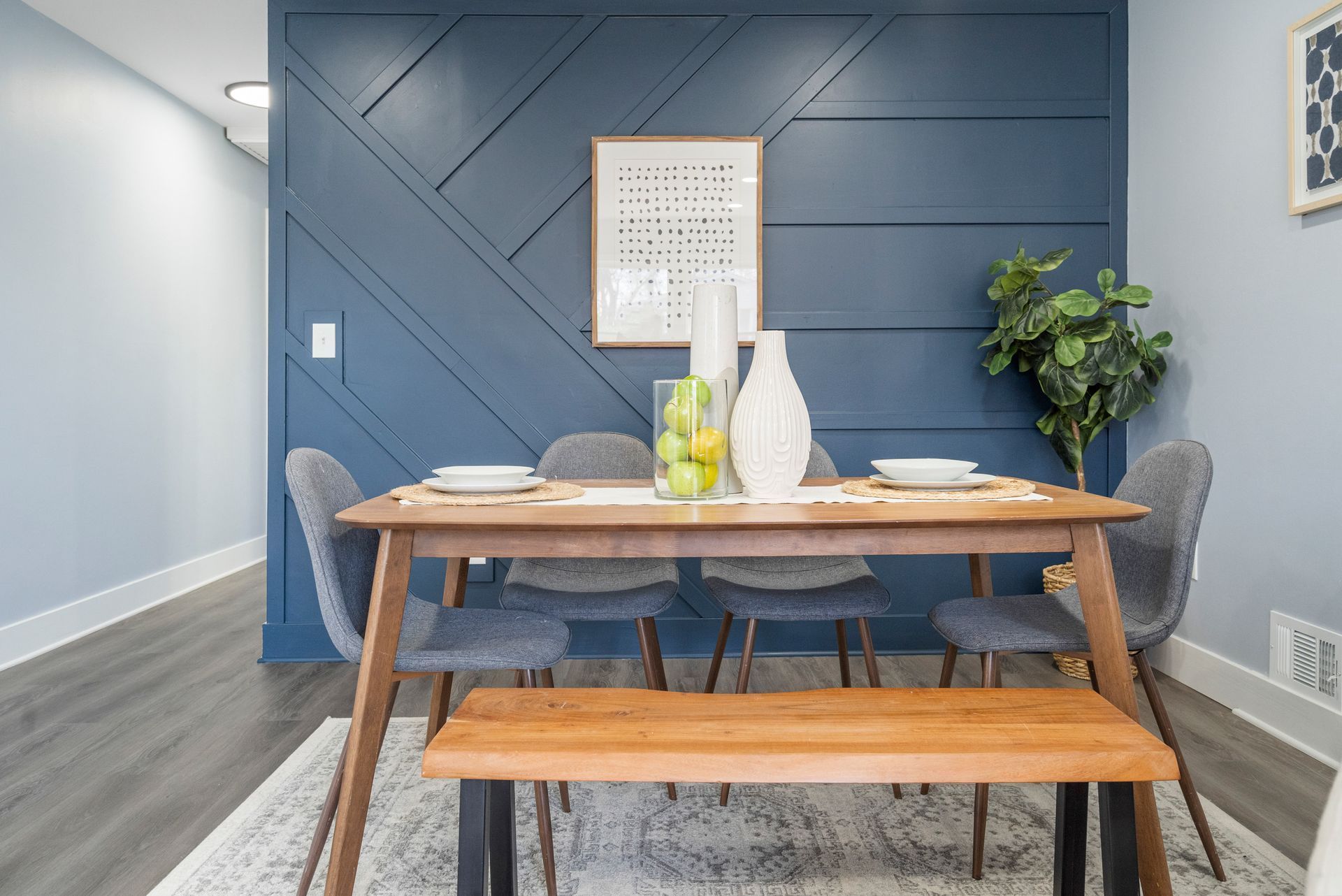 A dining room with a table and chairs and a blue wall.