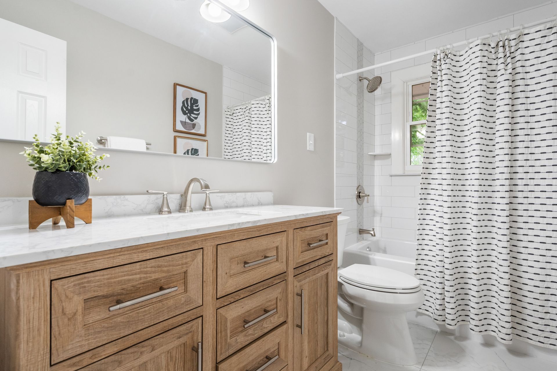 A bathroom with a sink , toilet , shower curtain and mirror.