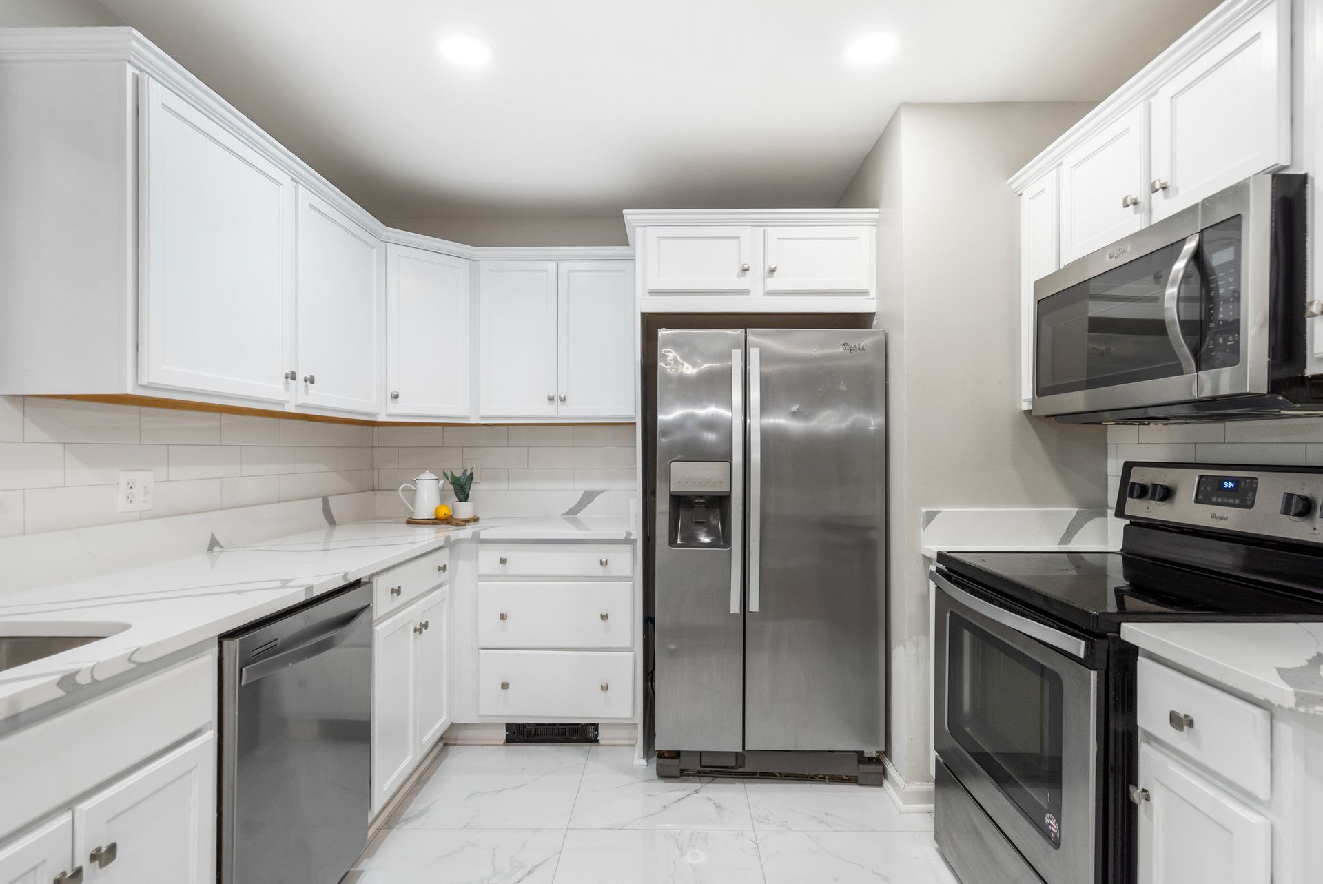 A kitchen with stainless steel appliances and white cabinets.