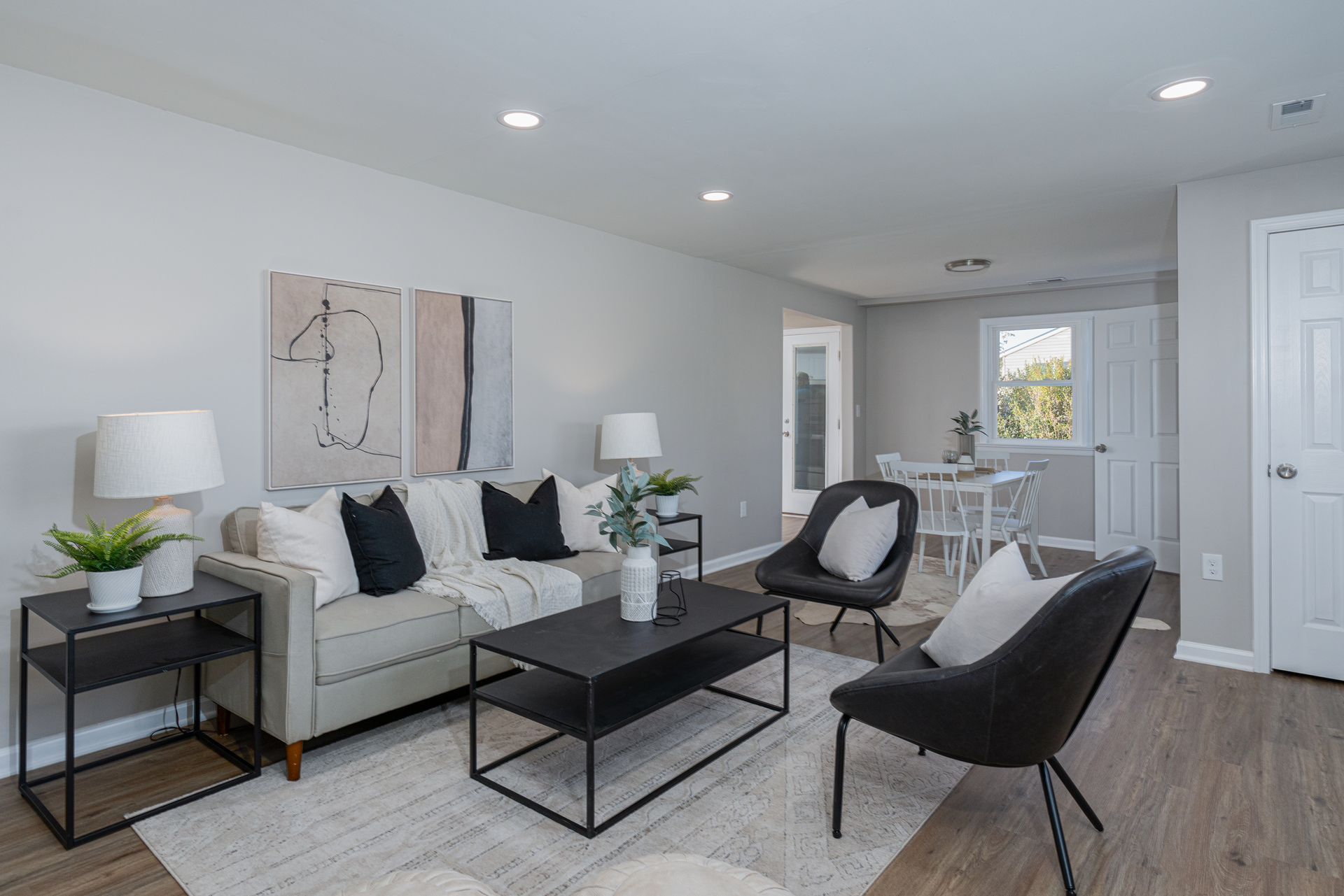 A living room with a couch , chairs , coffee table and lamps.