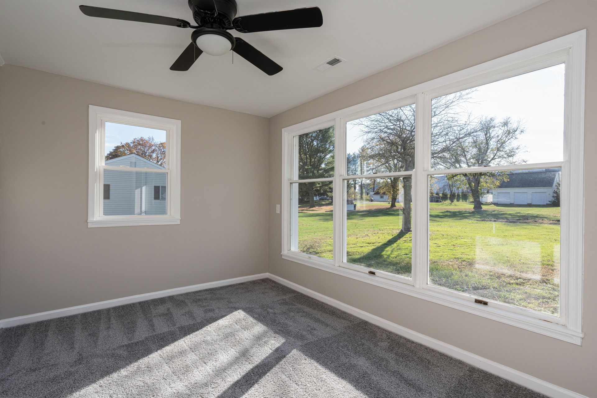 A room with a lot of windows and a ceiling fan.
