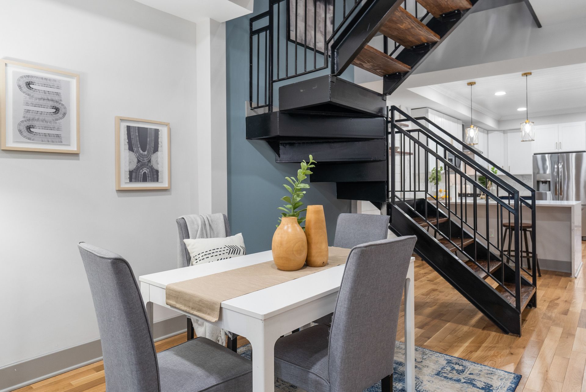 A dining room with a table and chairs and stairs leading up to the second floor.