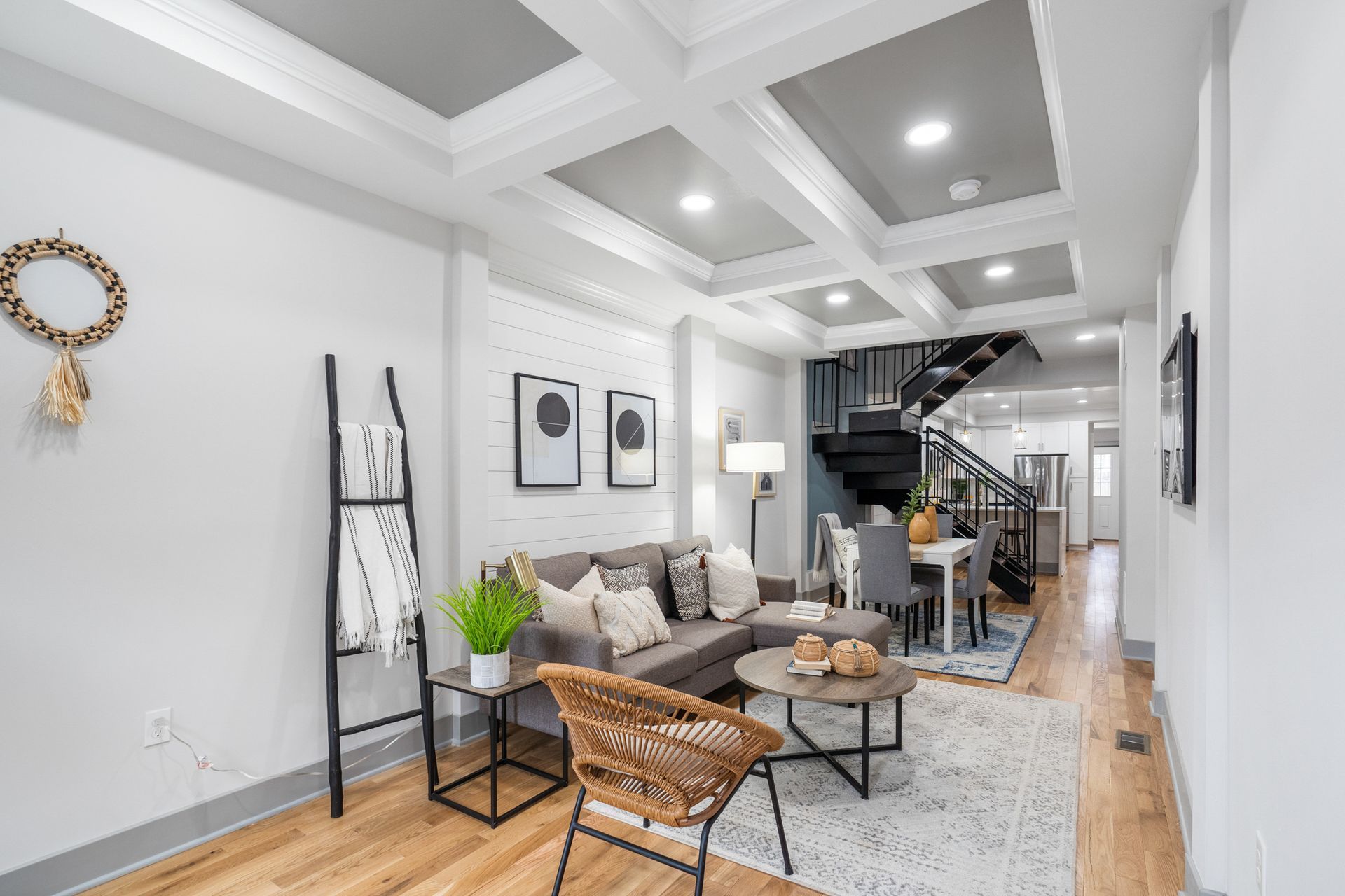 A living room with a couch , chair , table and stairs.