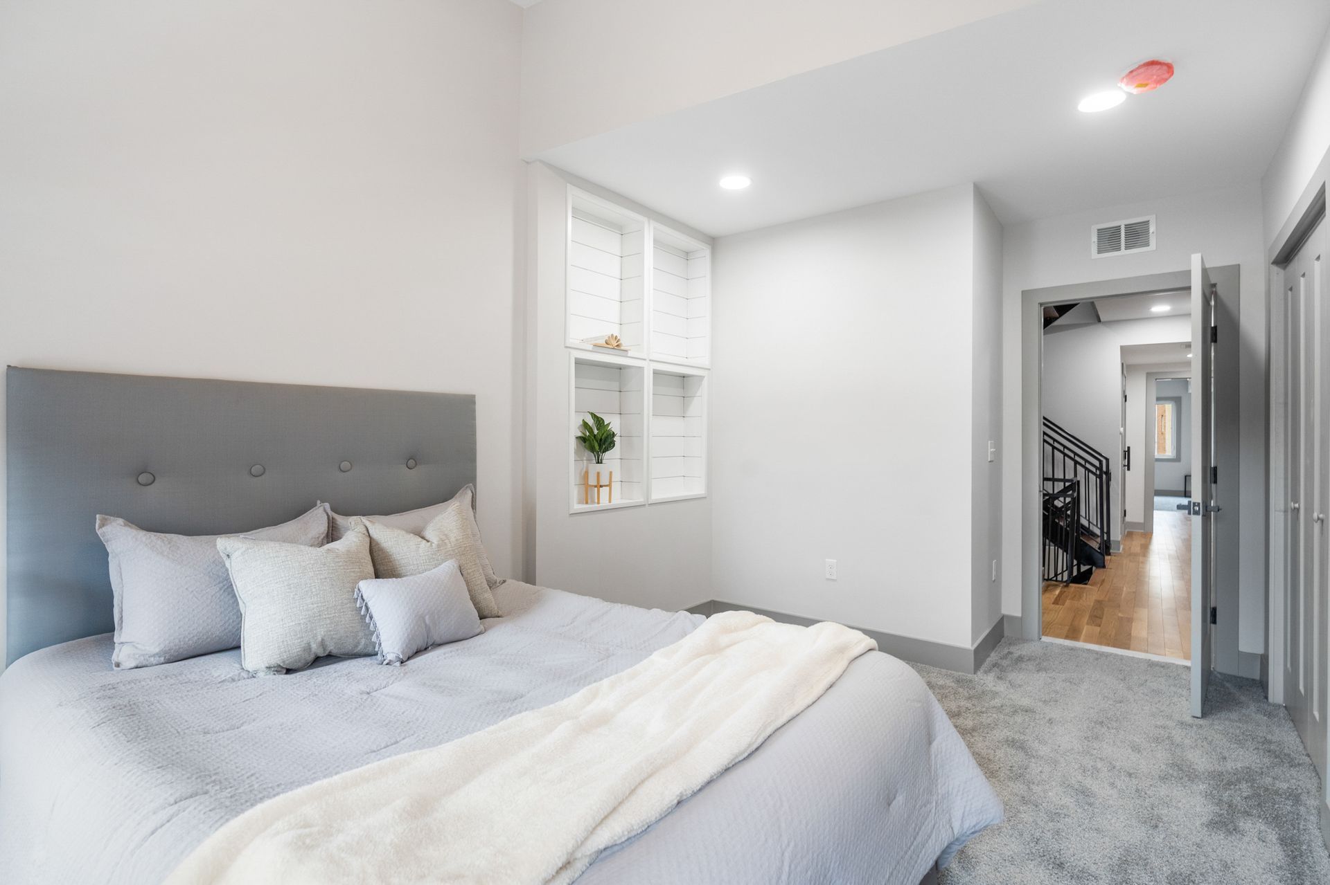A bedroom with a large bed and a staircase leading to the second floor.
