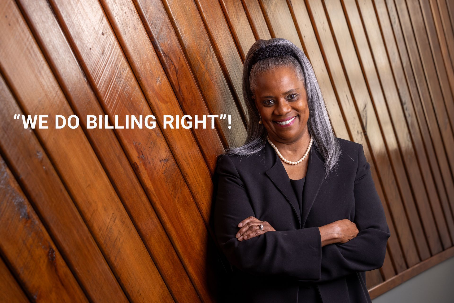 A woman leaning against a wooden wall with the words 