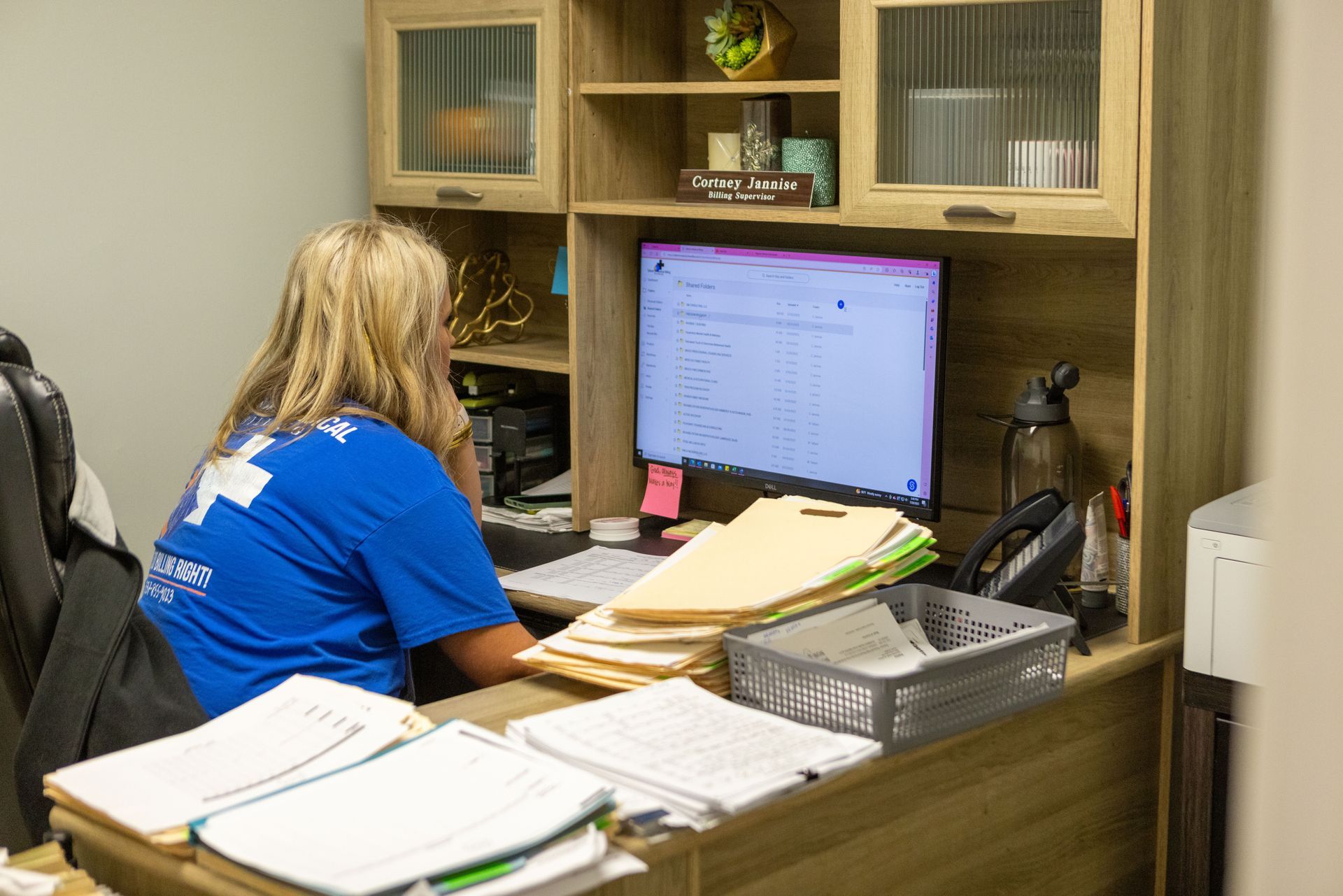 A woman is sitting at a desk in front of a computer.