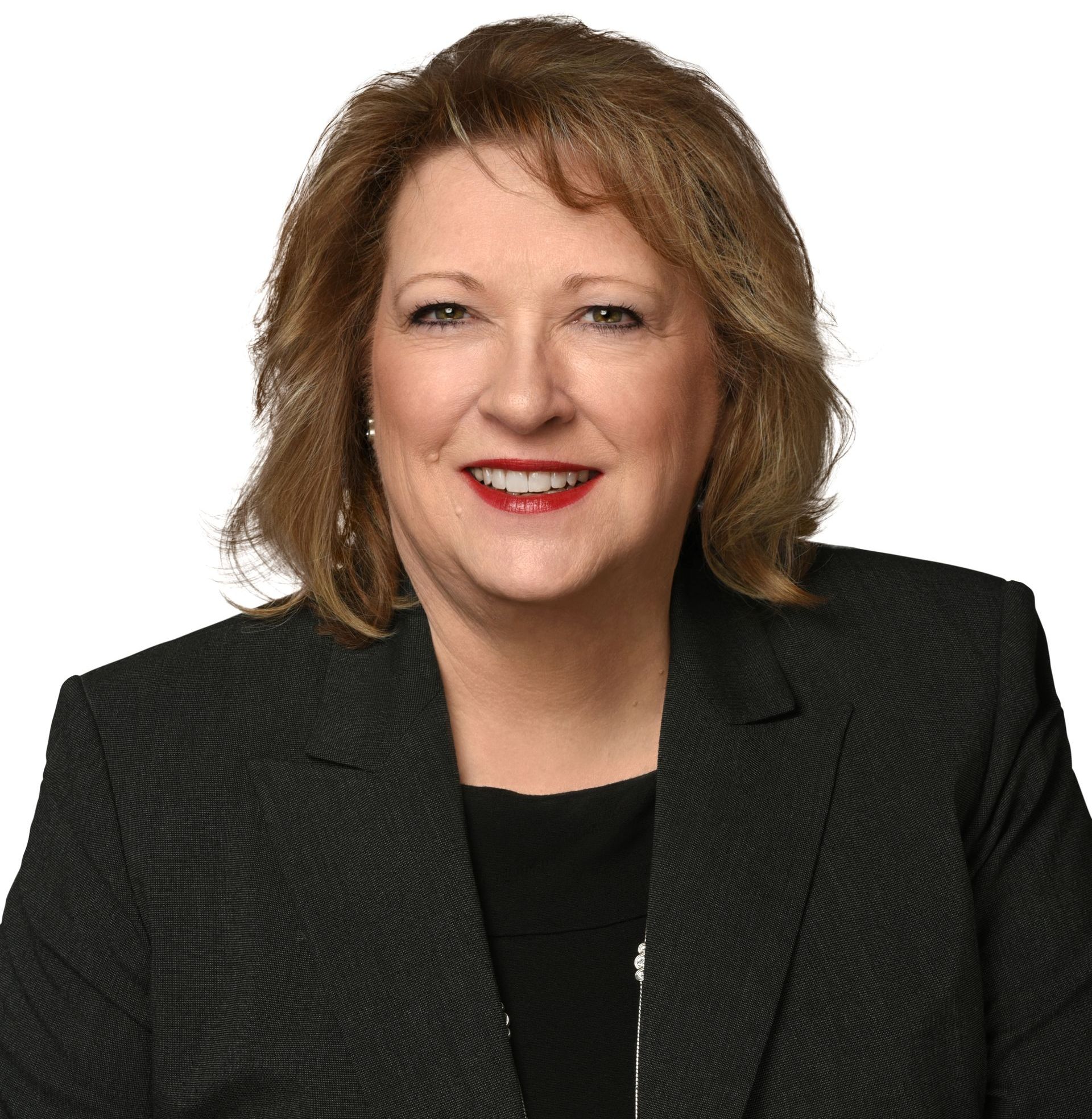 A woman is wearing a black jacket and smiling for the camera.
