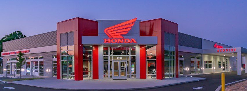 The front of a honda motorcycle dealership at dusk.