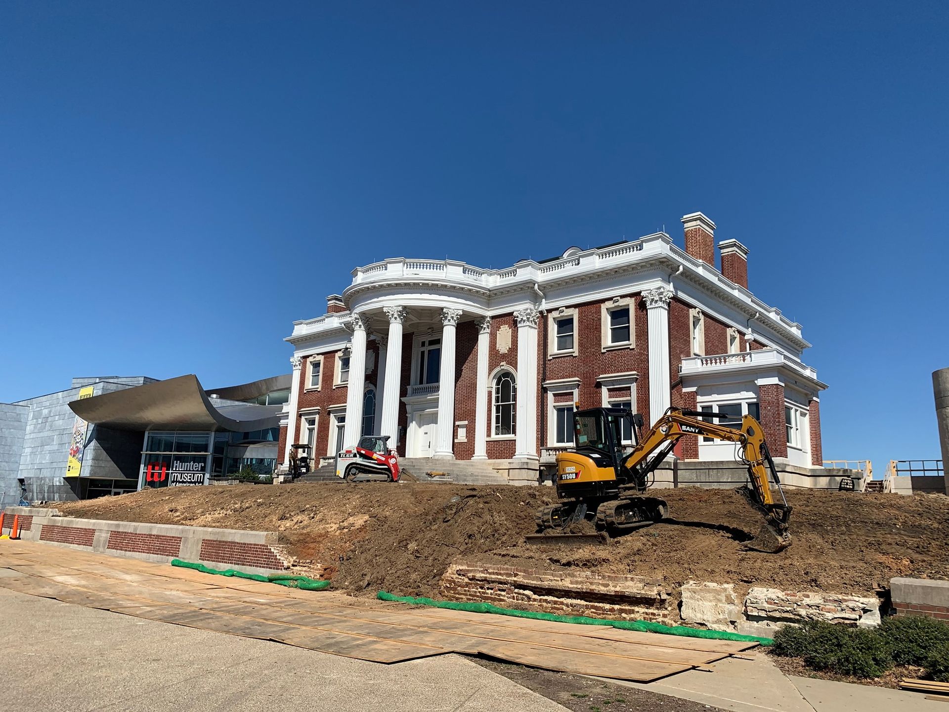 A large brick building with a yellow excavator in front of it.