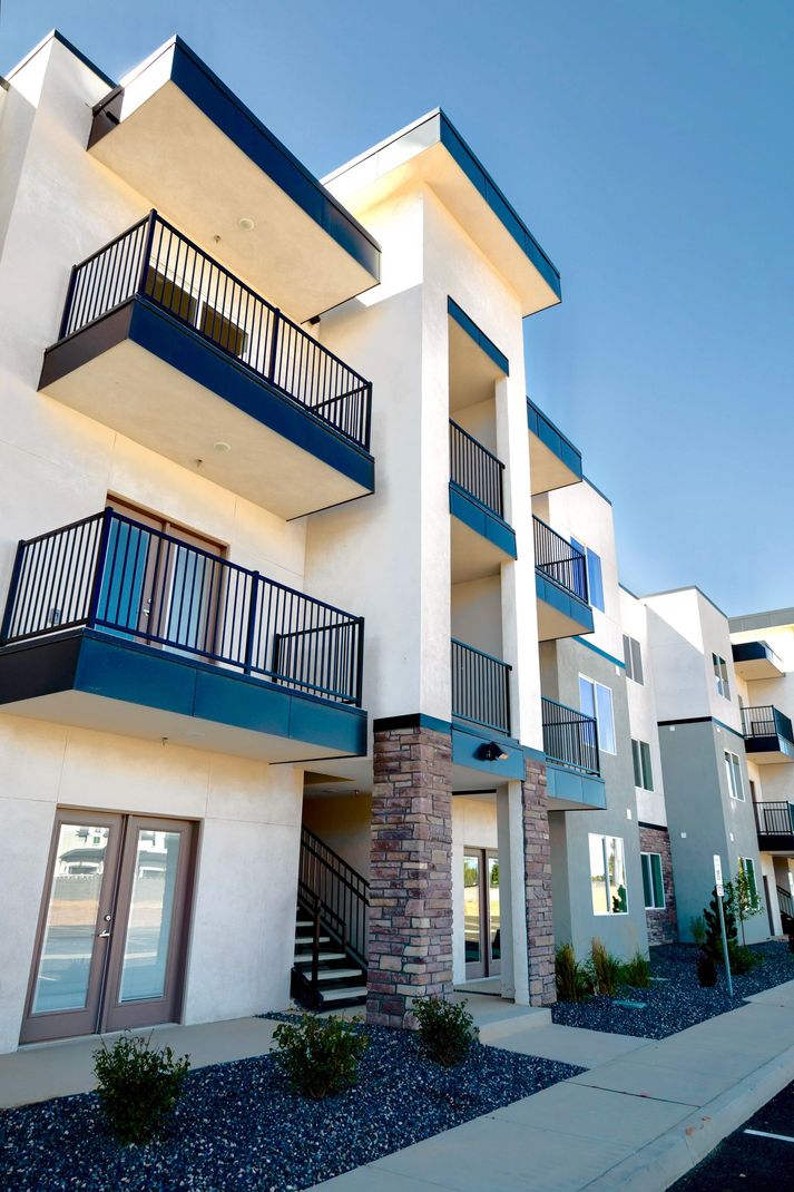 A white apartment building with blue balconies and stairs